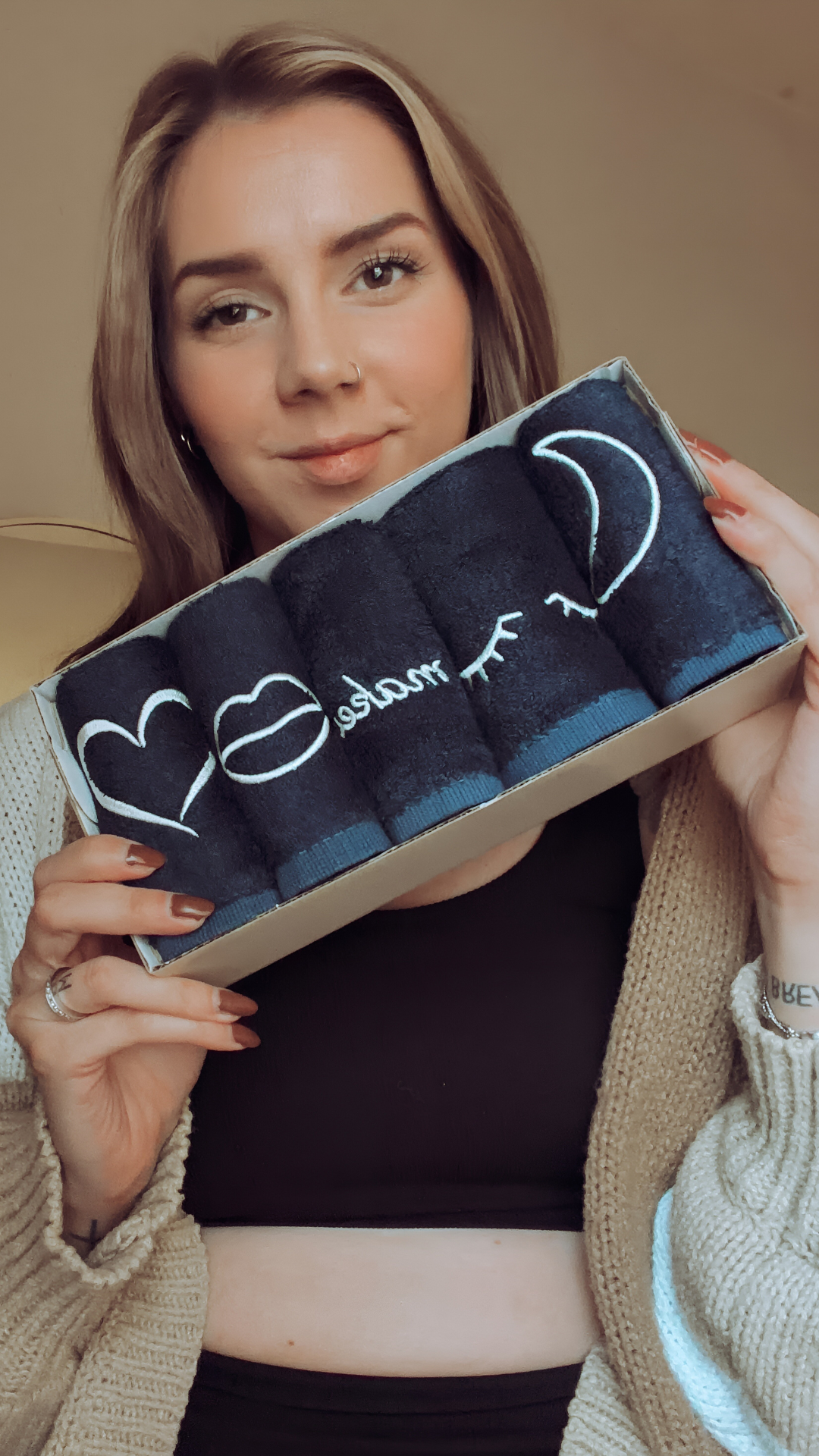 Person holding box of black towels with white designs.