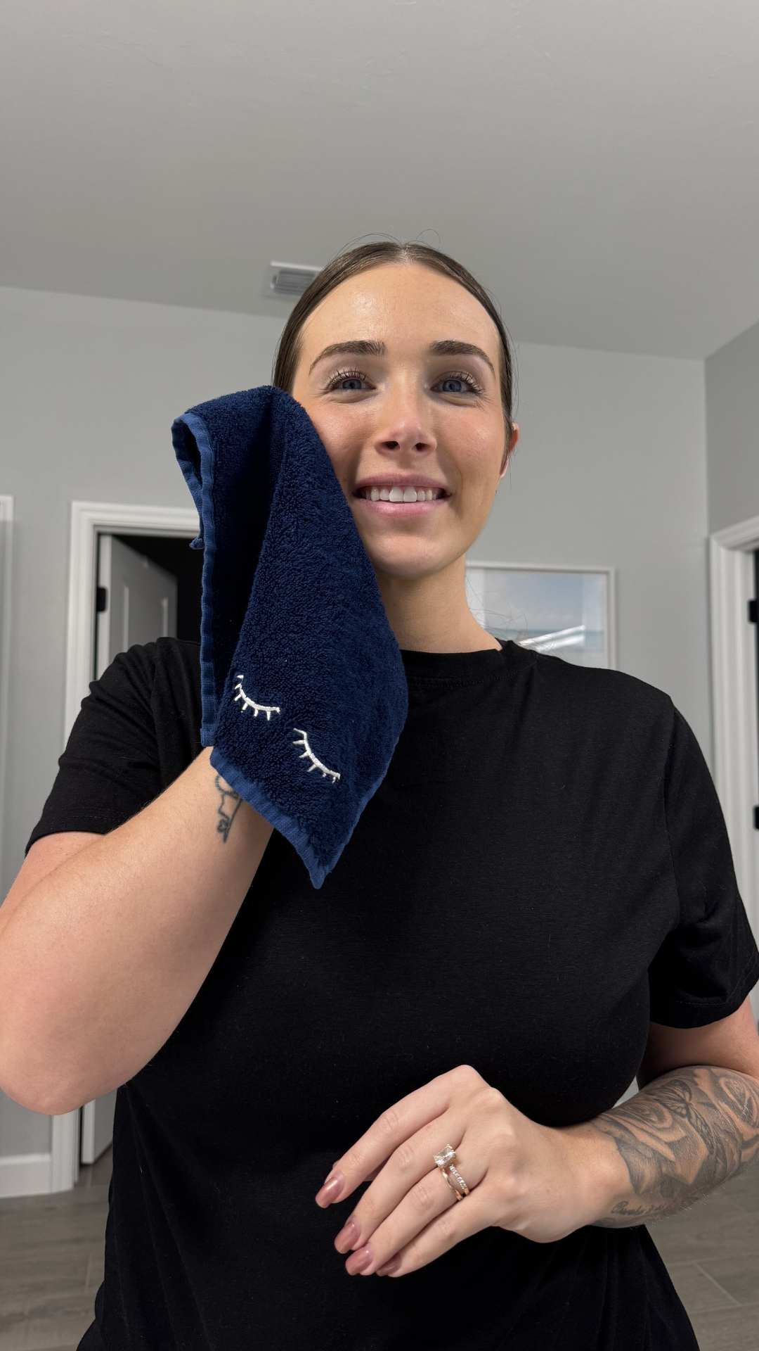 Person in a black shirt using a navy towel with closed-eye design on it.