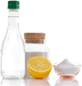 Bottle, jar with powder, lemon half, and powder on small plate.