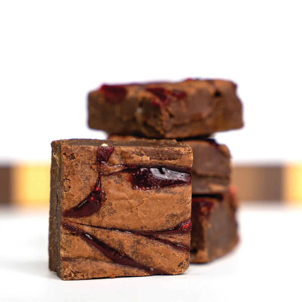 Stack of chocolate brownies with red swirl pattern on top.