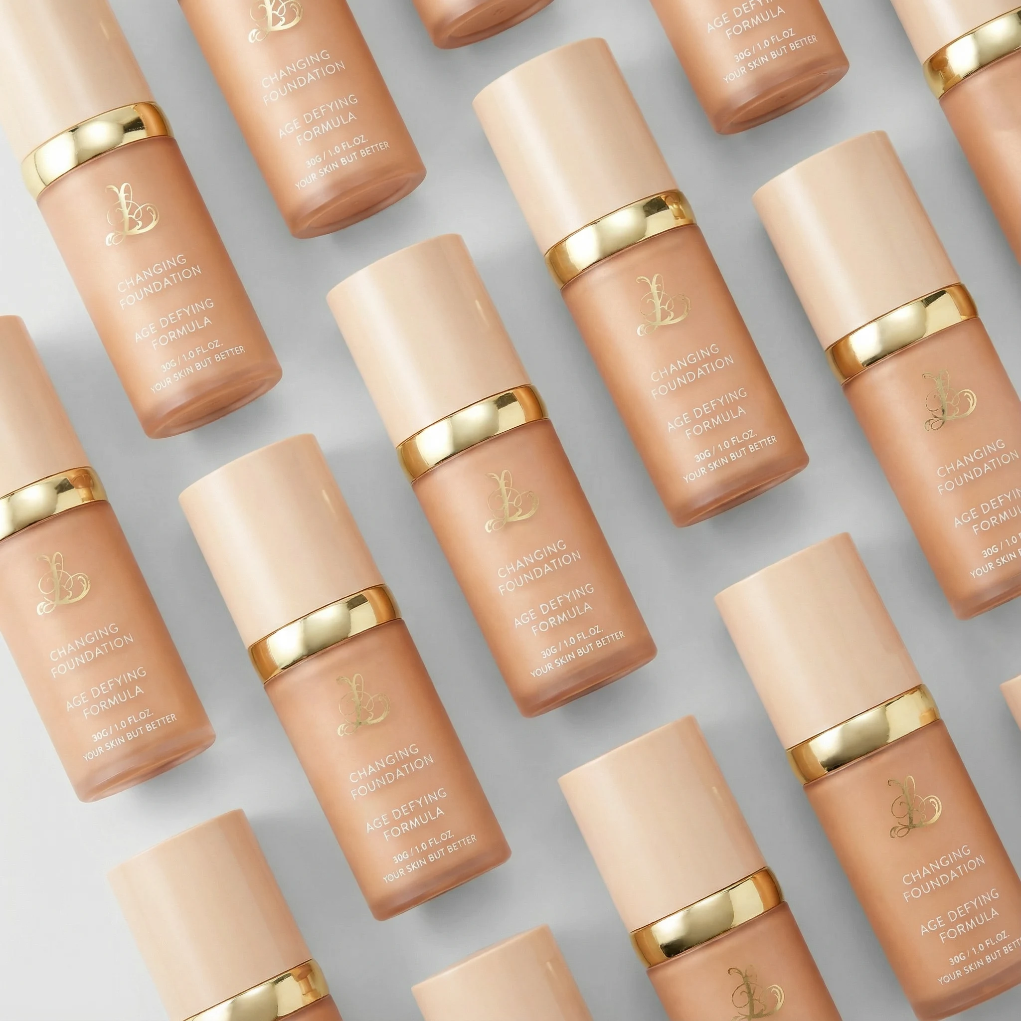 Multiple bottles of foundation arranged diagonally on a light background.