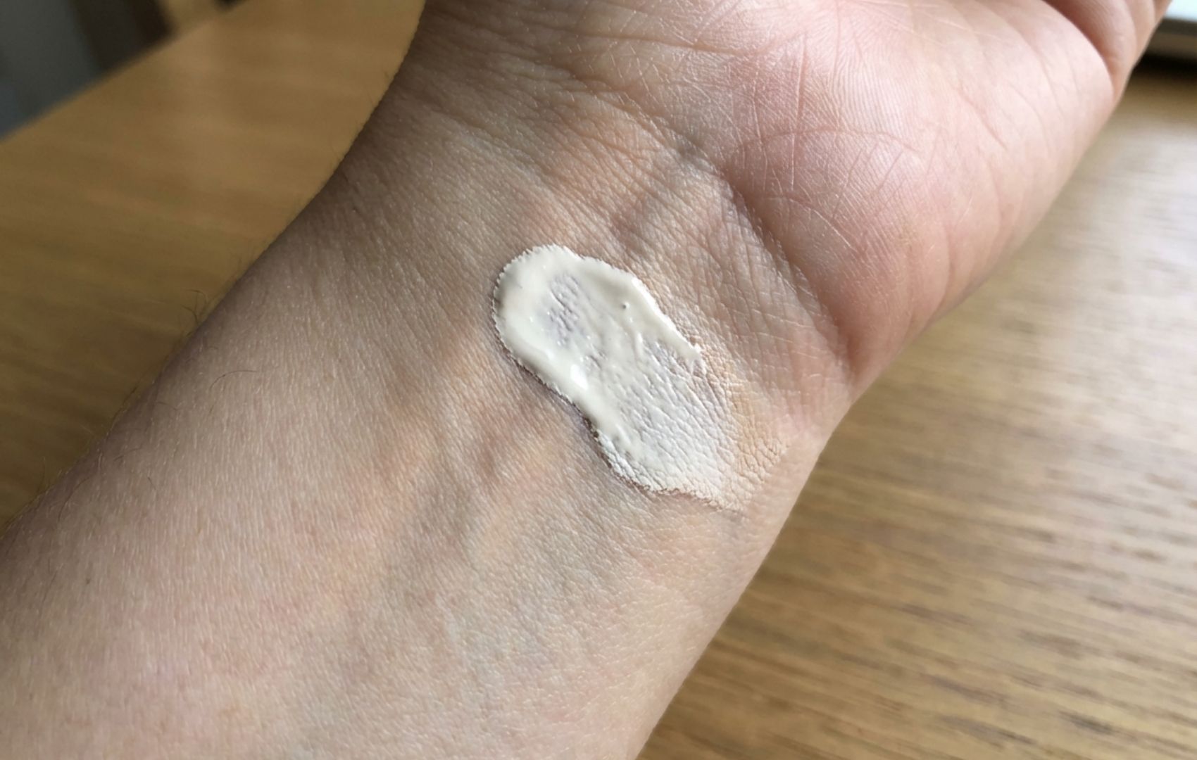 A close-up of a swatch of light-colored makeup on the inside of a wrist.