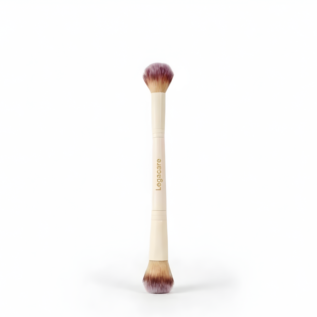 A double-ended makeup brush with a beige handle and purple-tipped bristles, standing vertically against a white background.
