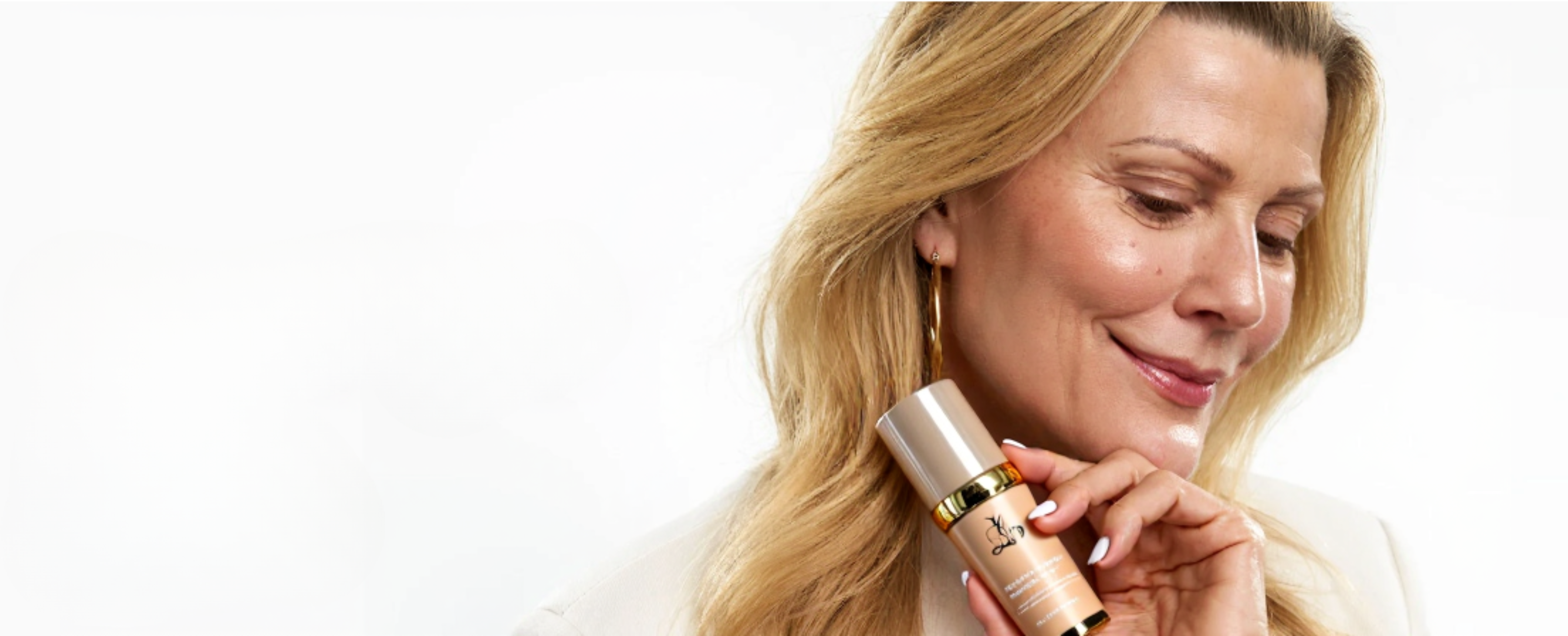 Person smiling, holding a cosmetic bottle, with a white background.