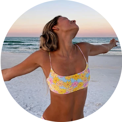 Person in floral bikini top enjoying a beach sunset.
