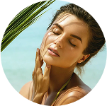 Woman enjoying sunlight on a beach, touching her face.