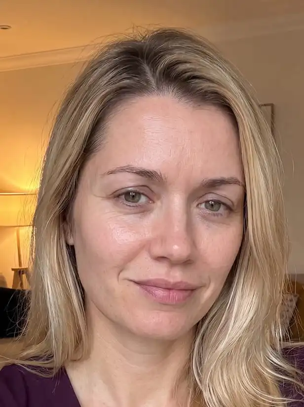 A close-up photo of a woman with blonde hair and light-colored eyes smiling slightly at the camera.