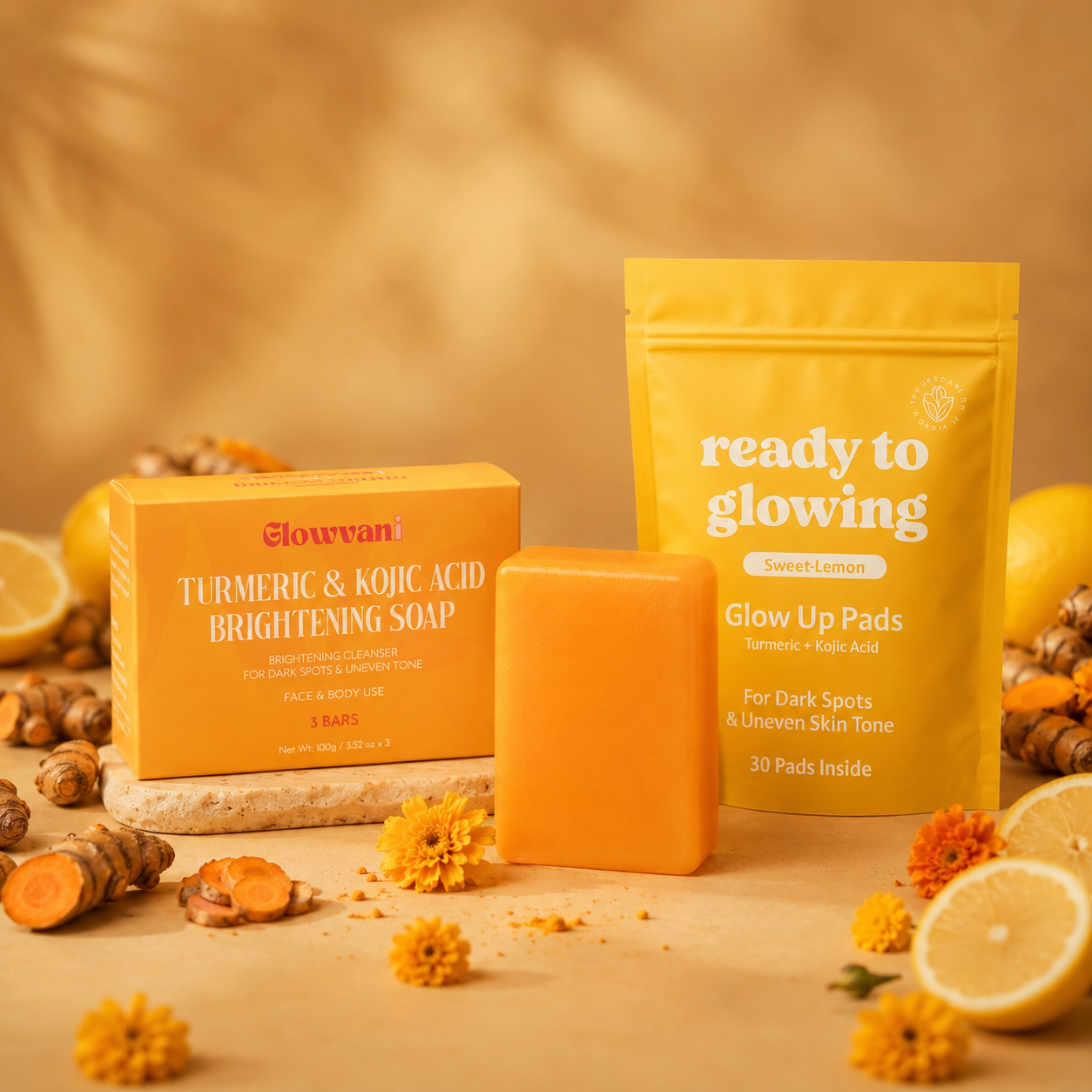 Glowvani turmeric soap and glow pads arranged with fresh turmeric, lemons, and small orange flowers.