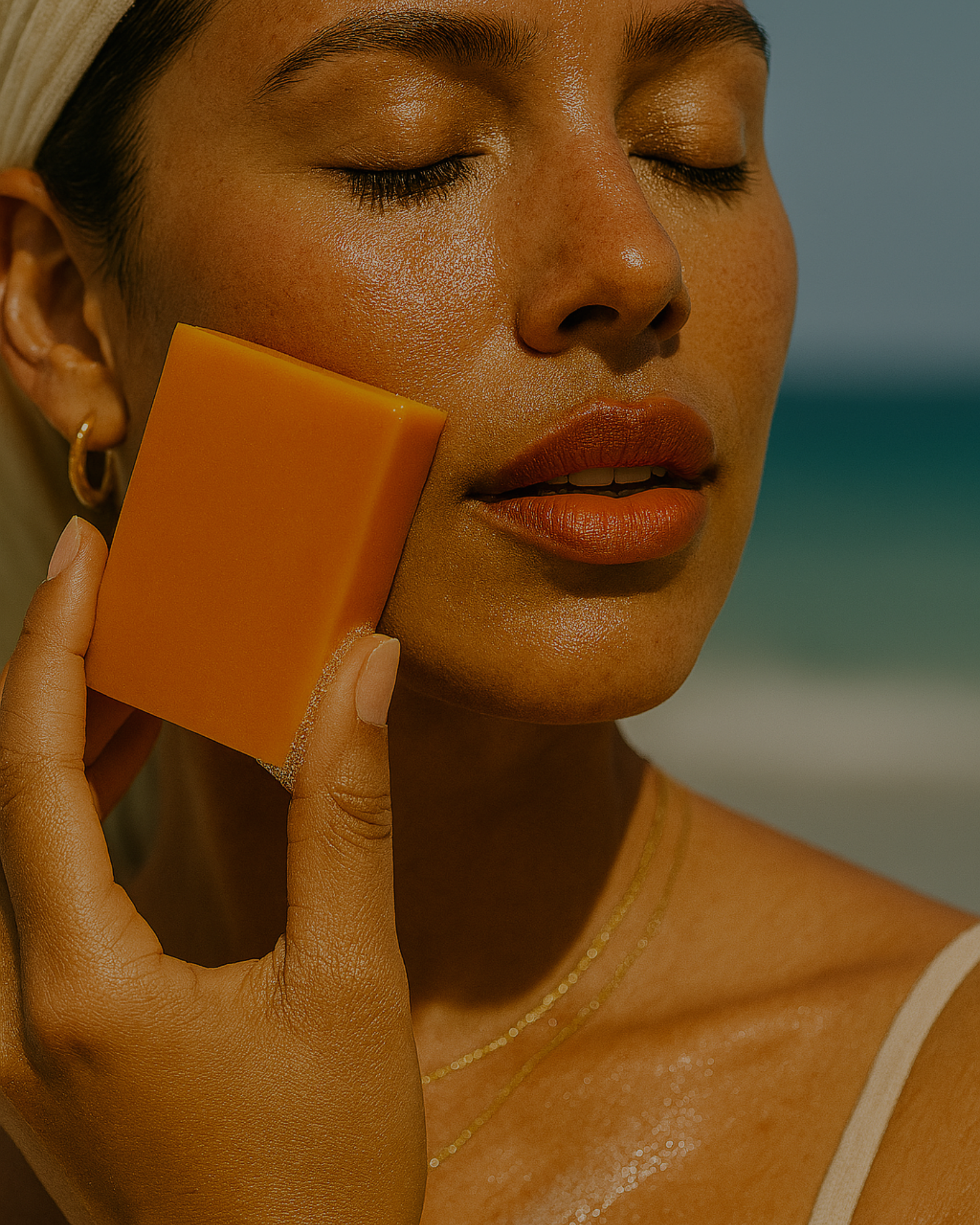 Person holding an orange soap bar against their face.