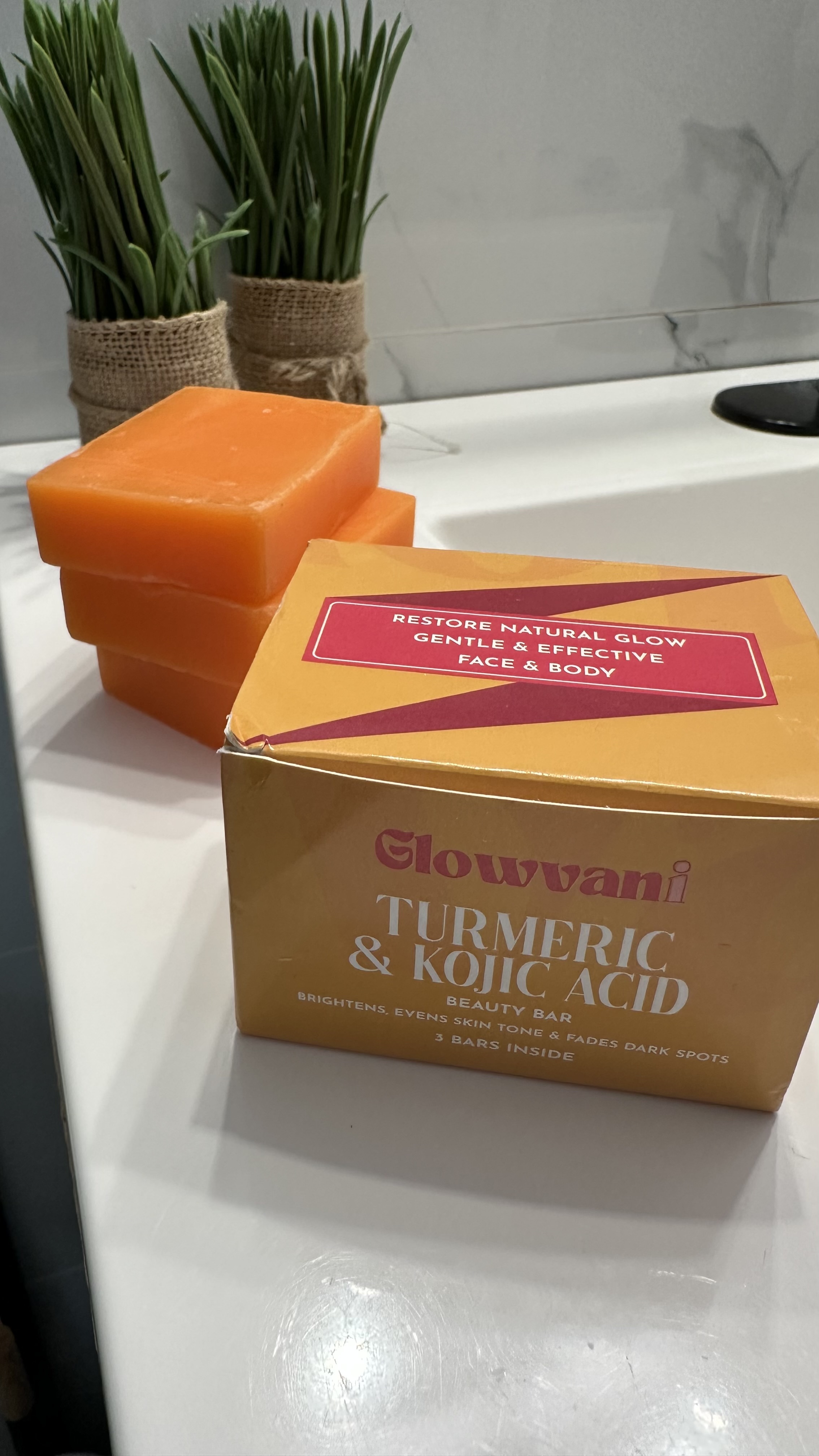 Box of turmeric and kojic acid soap bars on a bathroom counter.