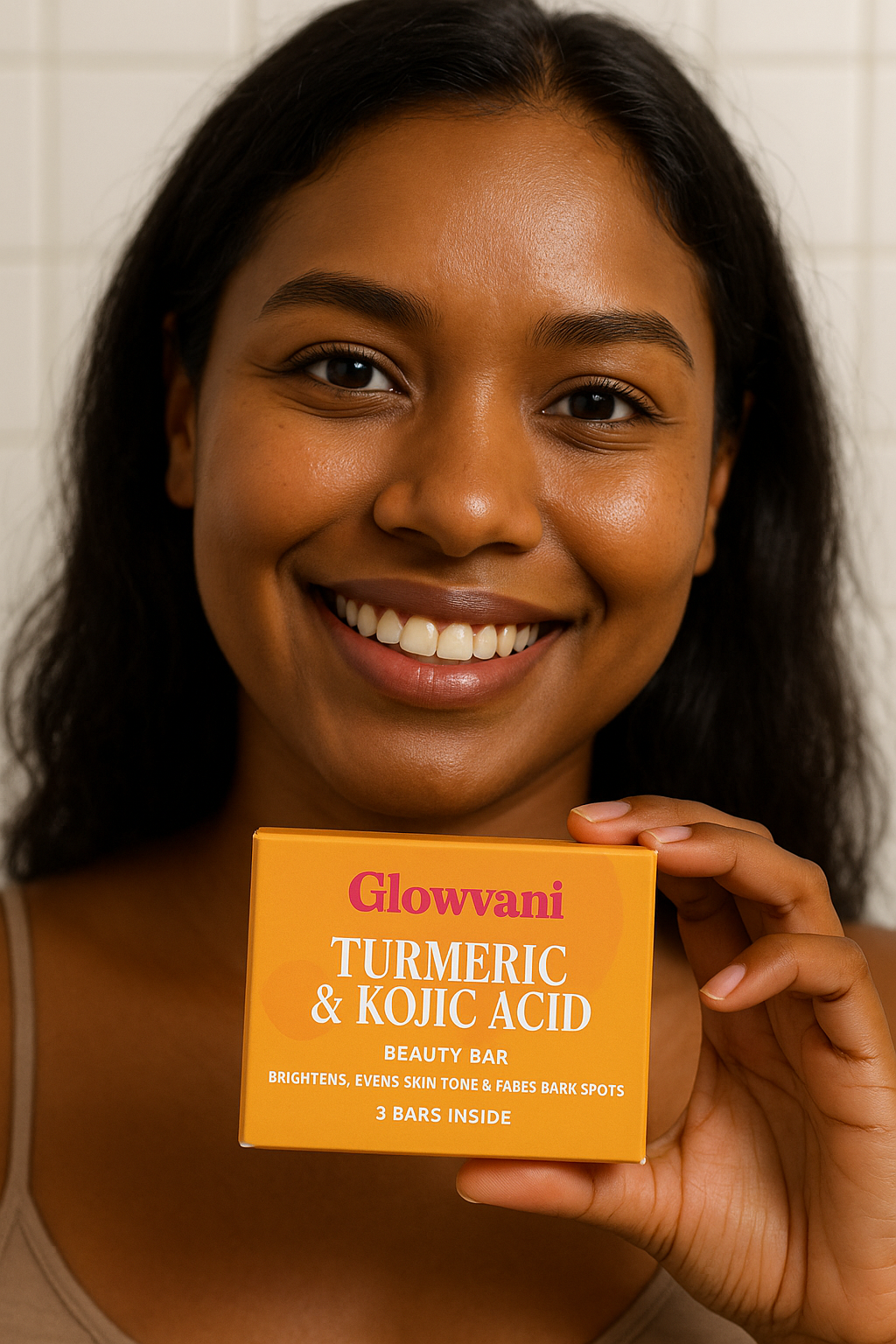 Person smiling, holding a Glowvani Turmeric & Kojic Acid beauty bar box.