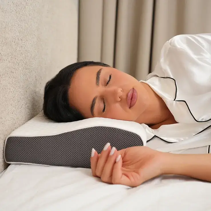 Person sleeping on a contoured pillow, wearing silk pajamas.