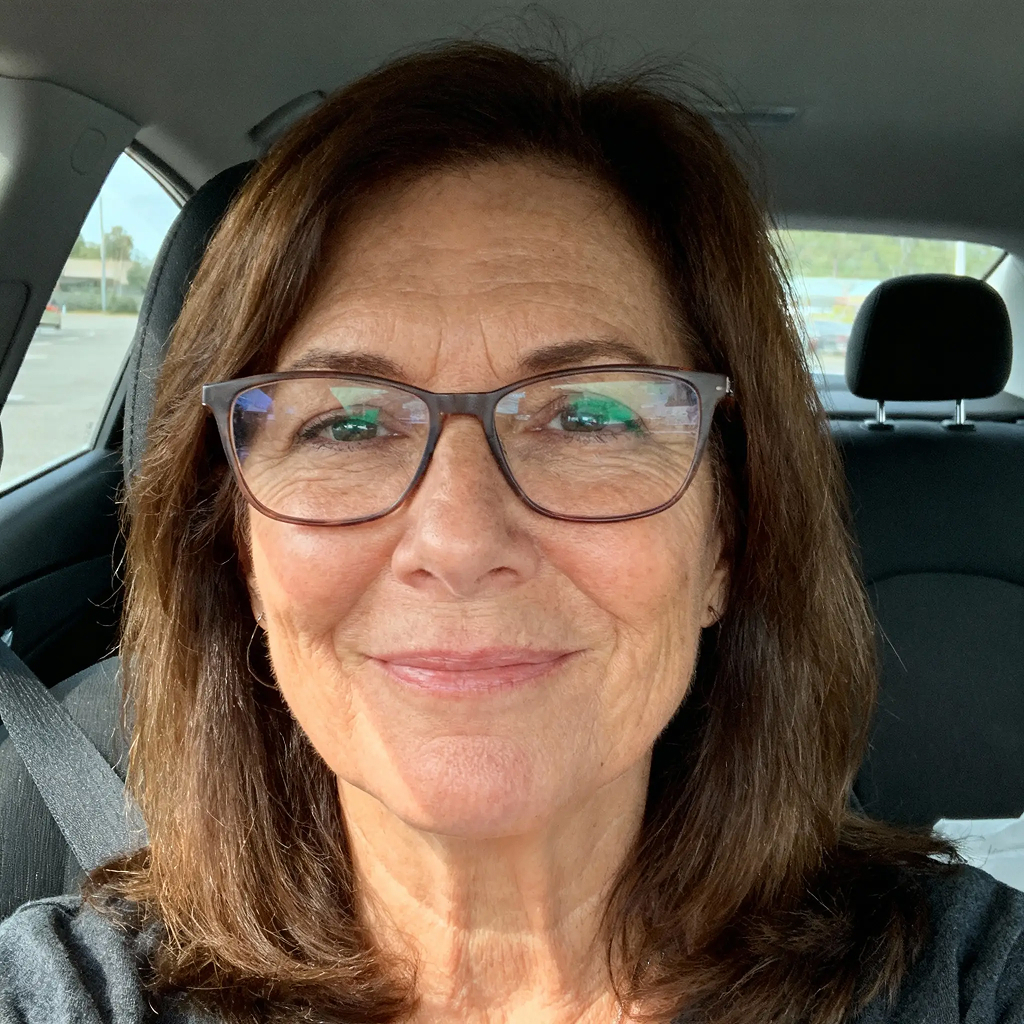 Person wearing glasses smiling in a car.