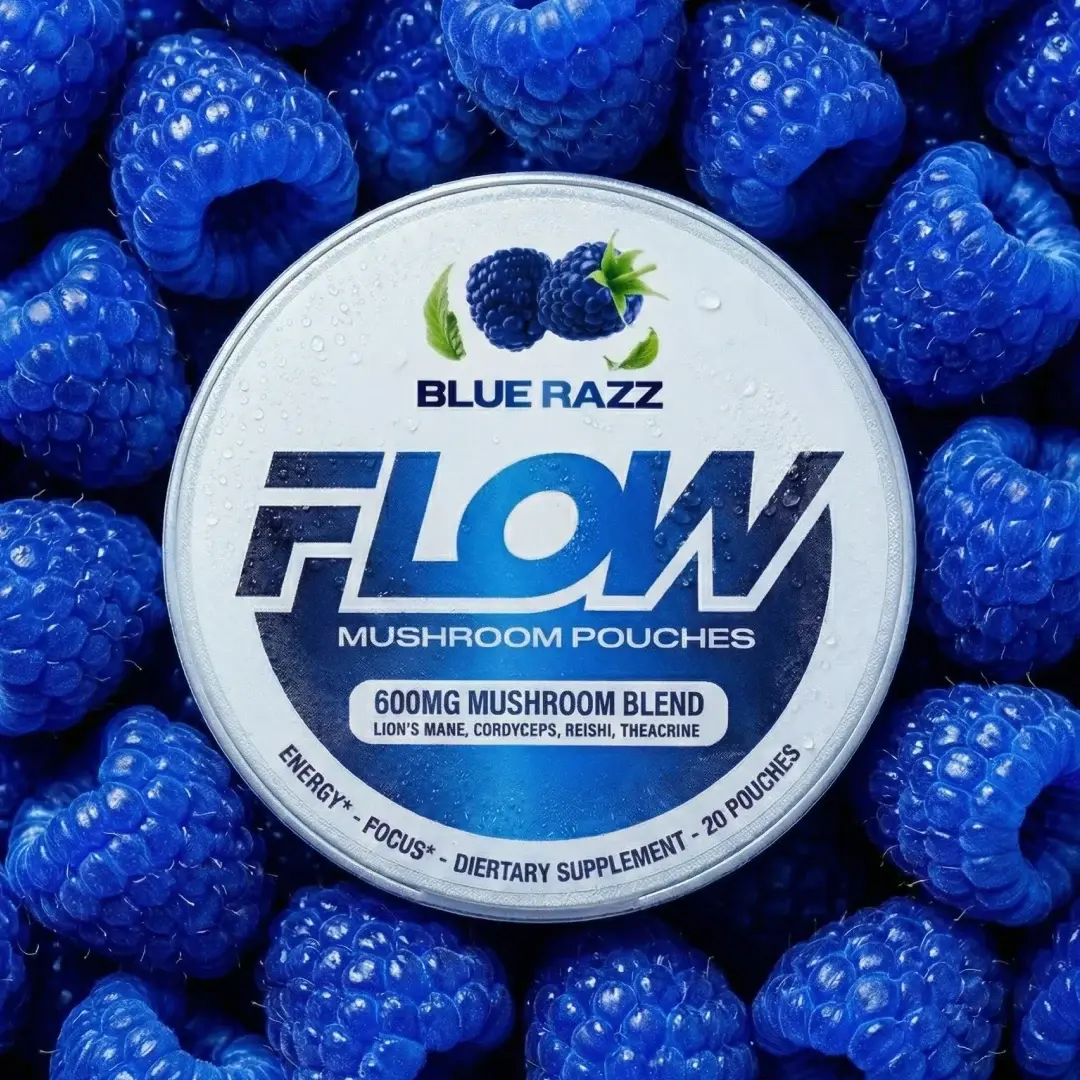 A tin of Flow Blue Razz Mushroom Pouches sits on a bed of vibrant blue raspberries.