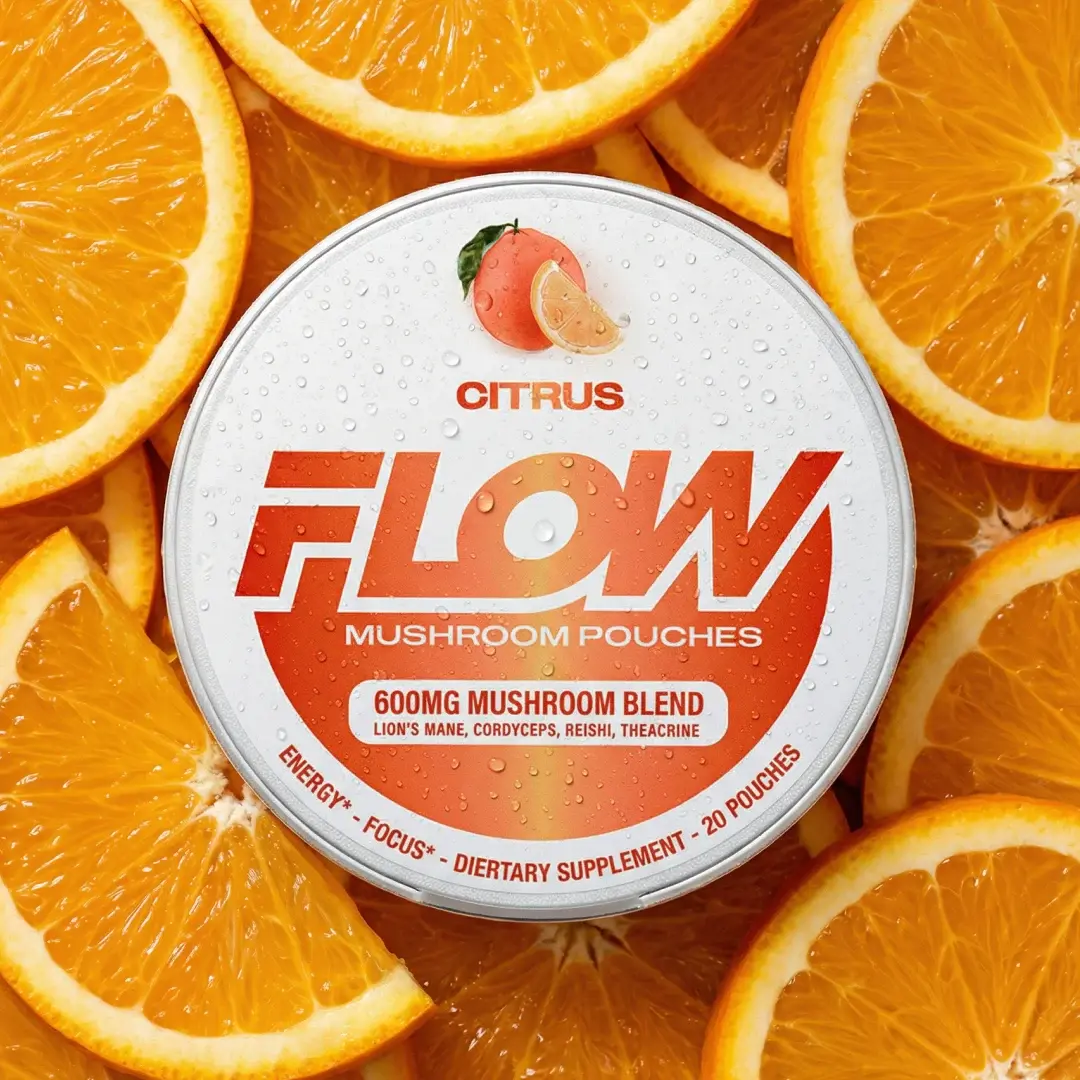 A round, white tin of Citrus Flow Mushroom Pouches rests on a bed of fresh orange slices.