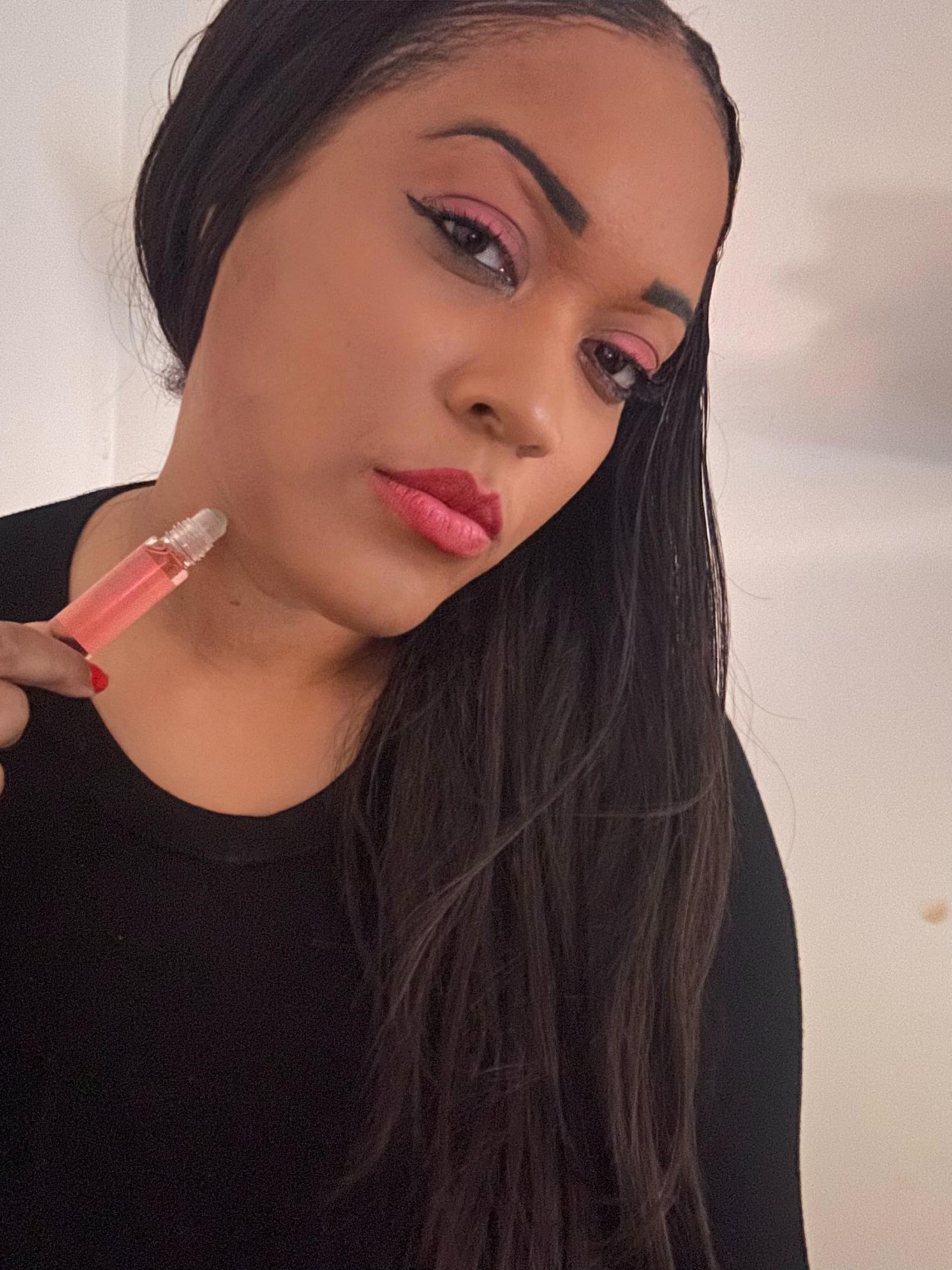 Woman applying lipstick with a serious expression.