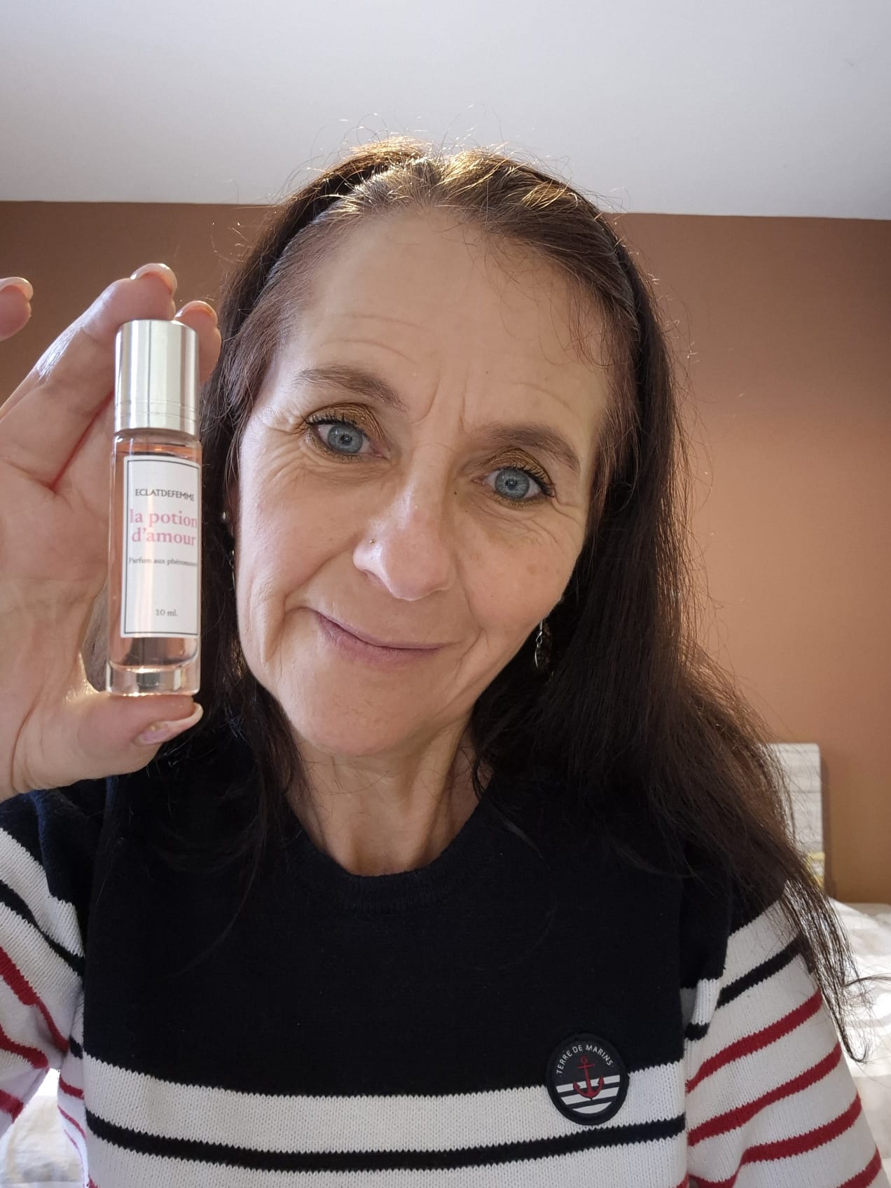 A person smiling, holding a bottle labeled 'la potion d'amour.'