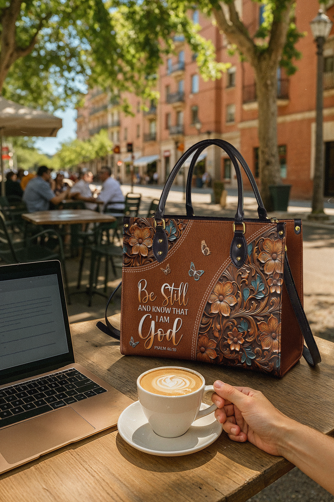 A decorative handbag on a table with a laptop and a cup of coffee.
