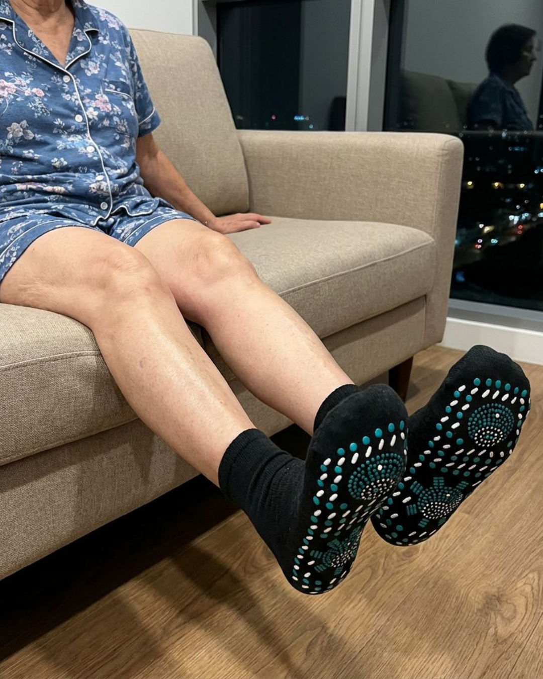Person wearing patterned grip socks sitting on a sofa.