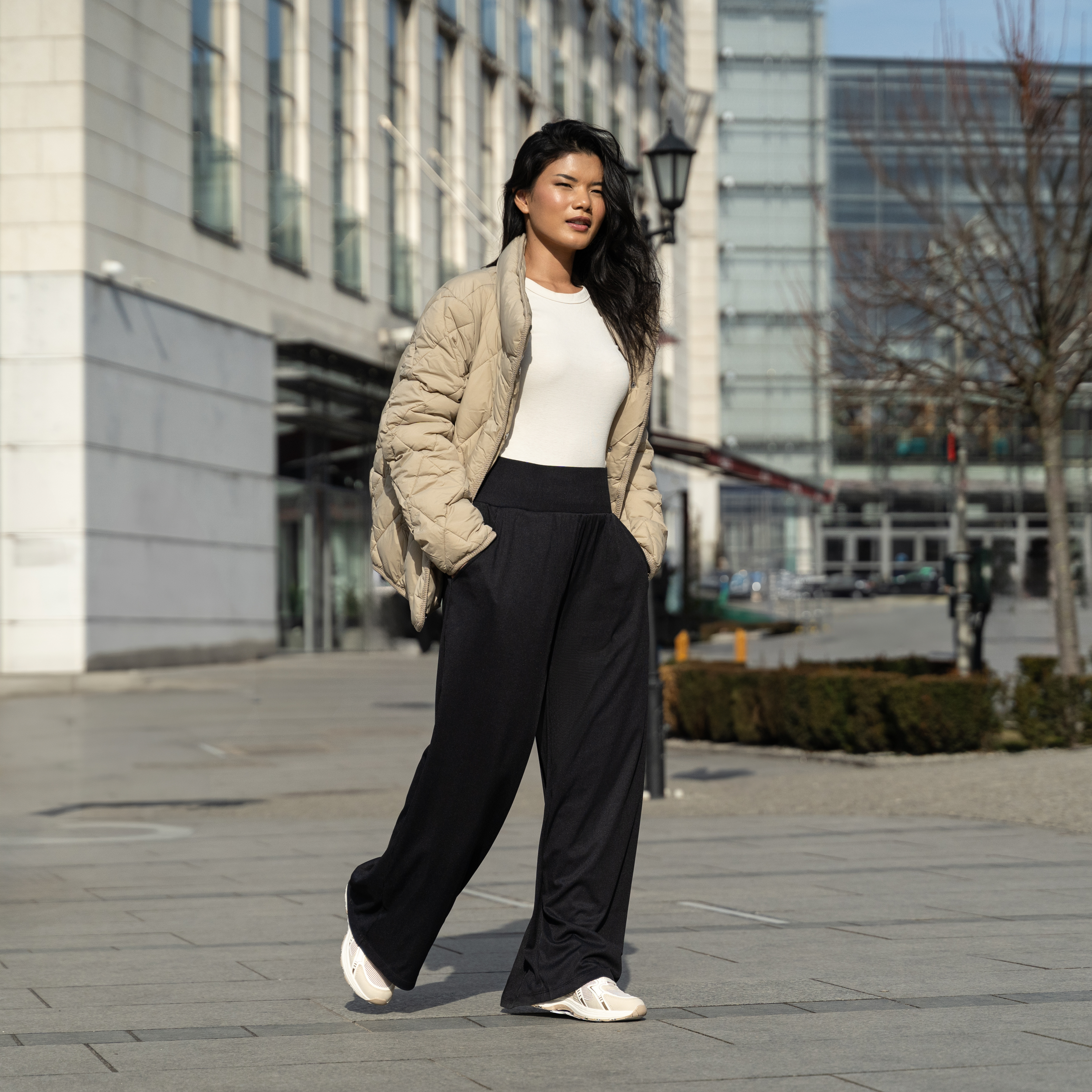 Woman in a stylish outfit walking in an urban outdoor setting.