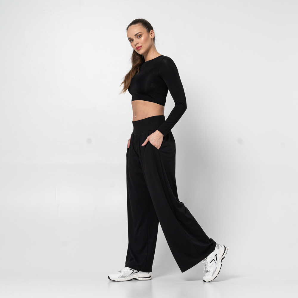 A woman in black activewear and sneakers posing against a plain white background.