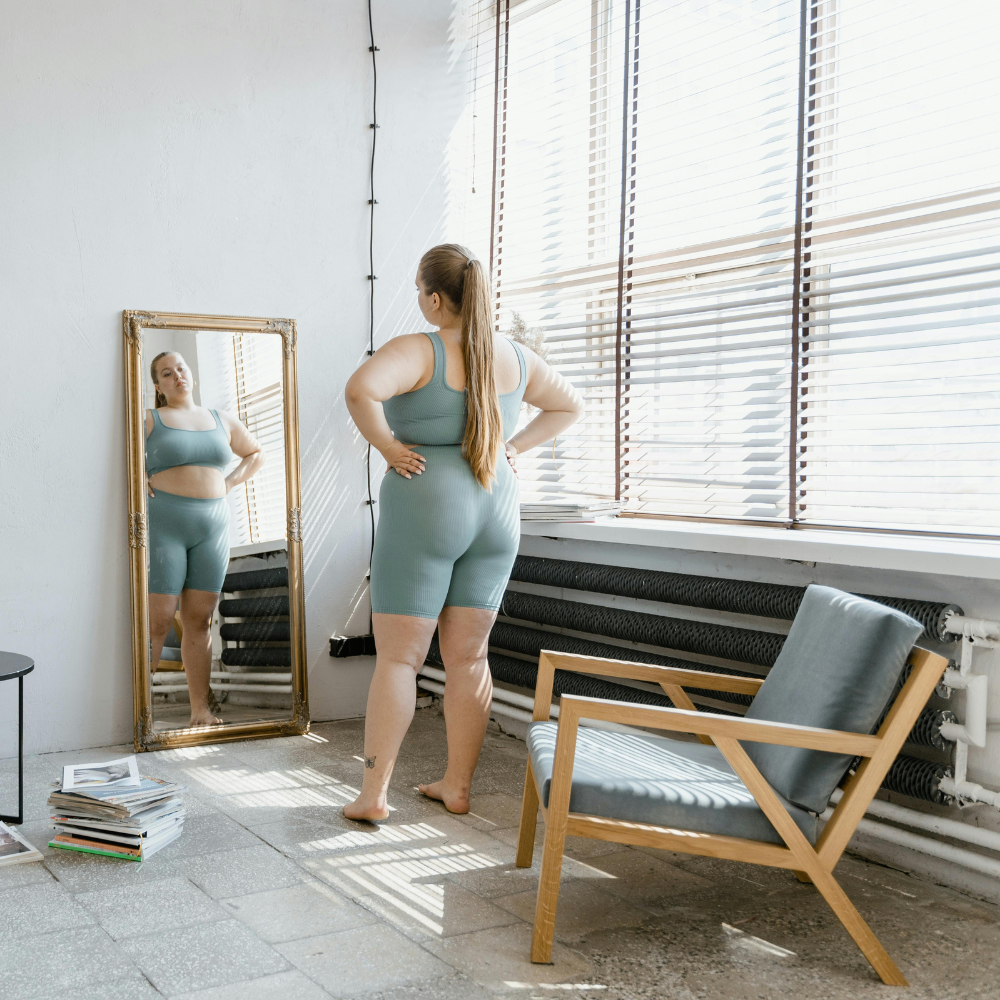 Person in workout attire looks at reflection in a large mirror.