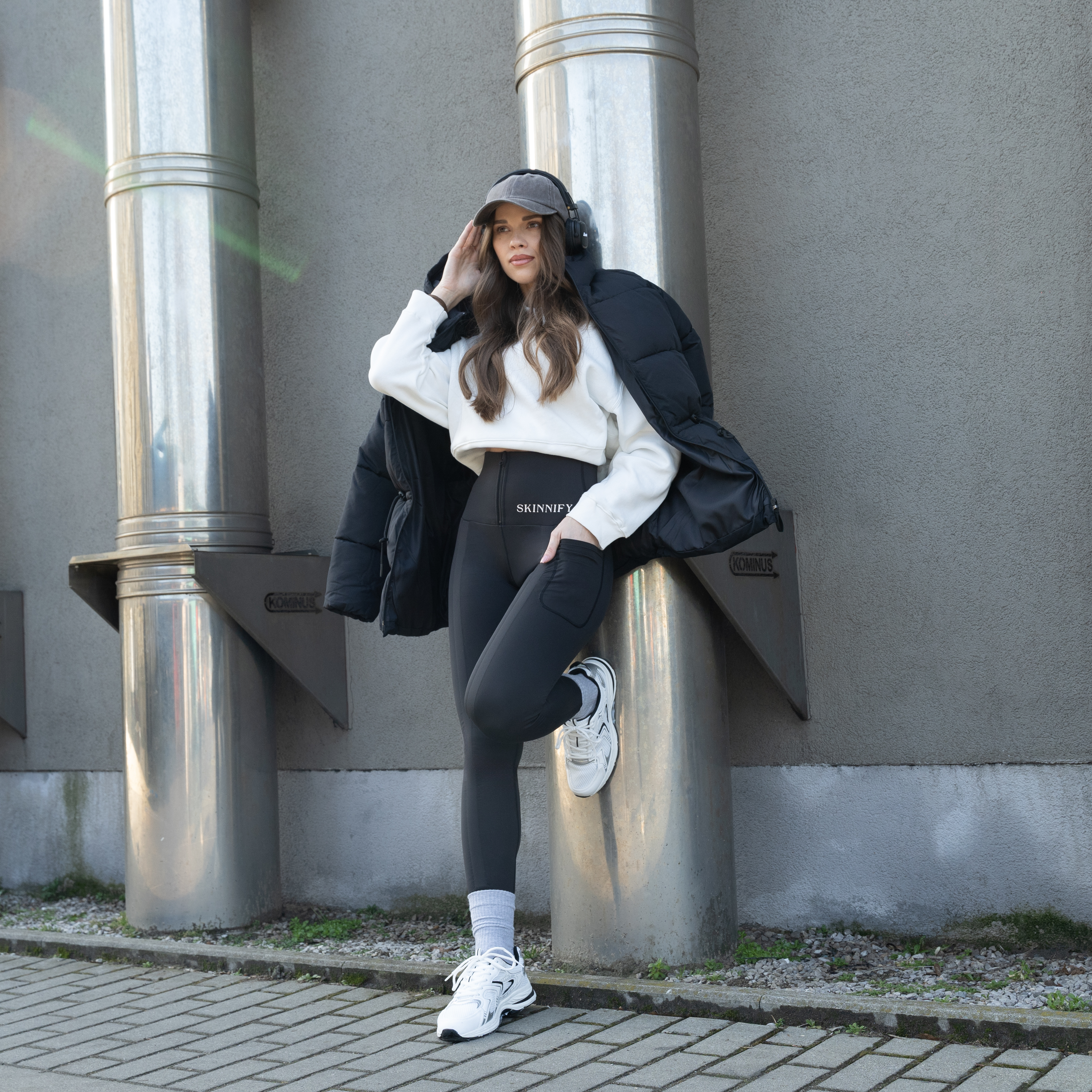 Person in casual wear leaning against metal pipes outdoors.