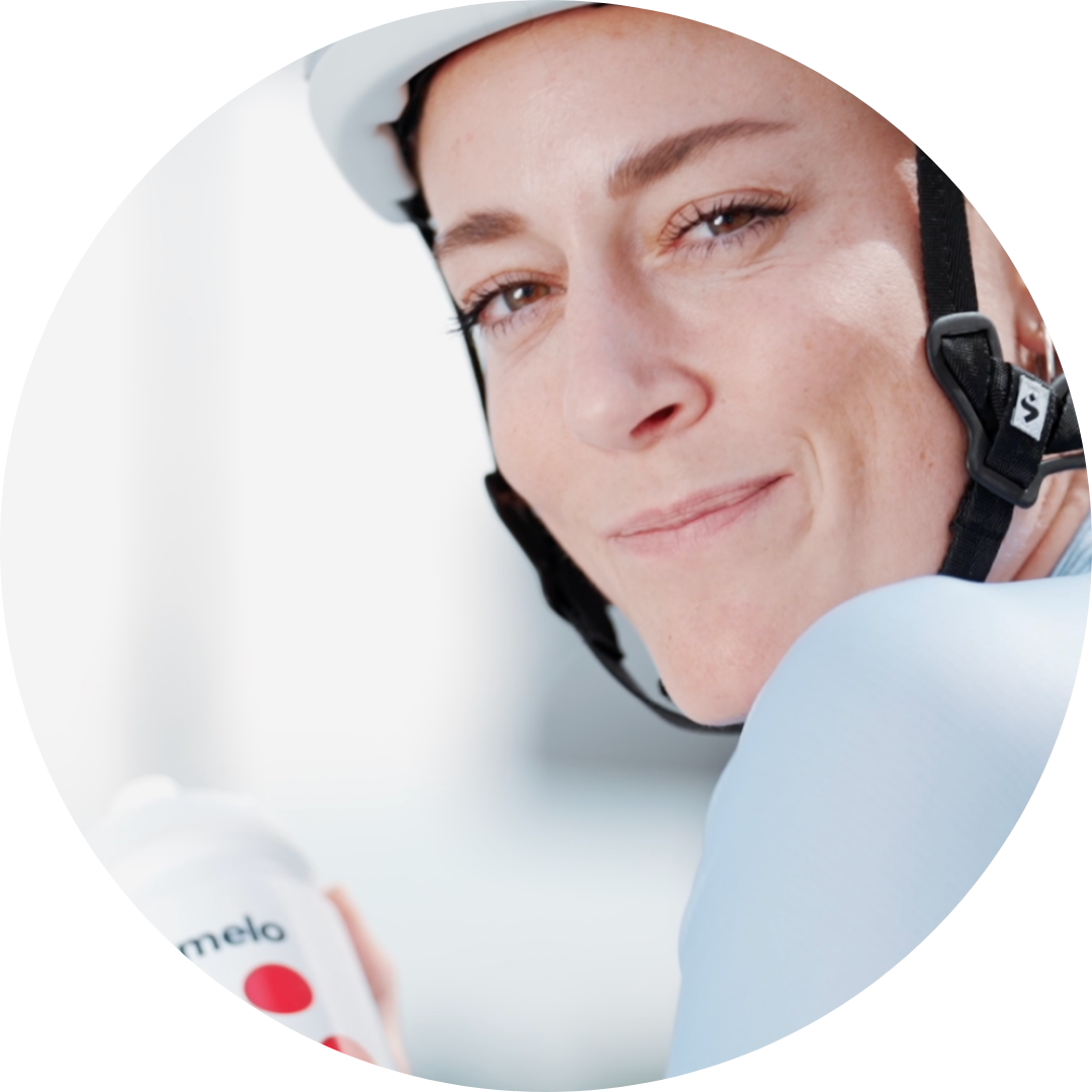 Person wearing a helmet, holding a water bottle, smiling.