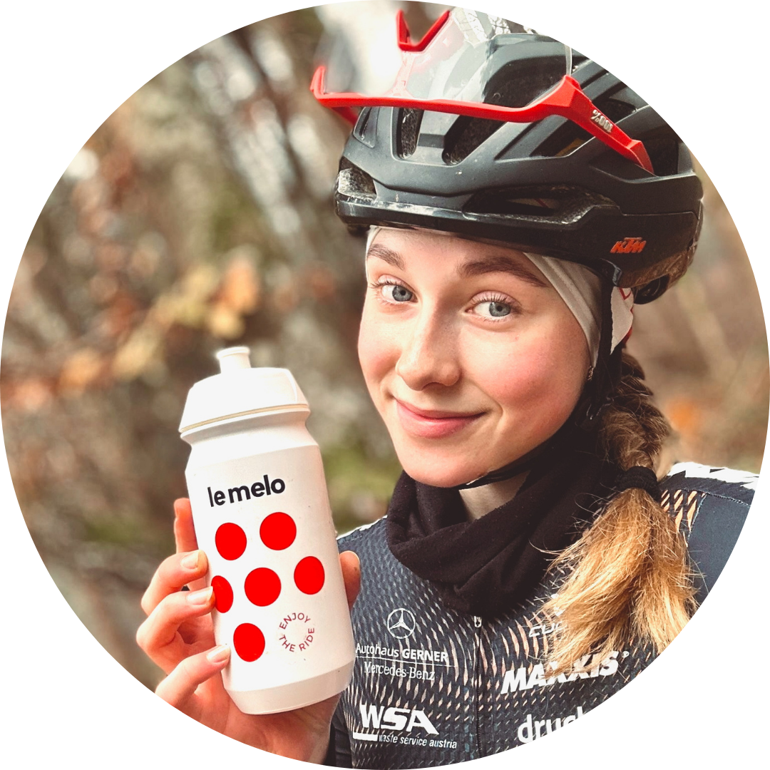 Person in cycling gear holding a water bottle with red dots.