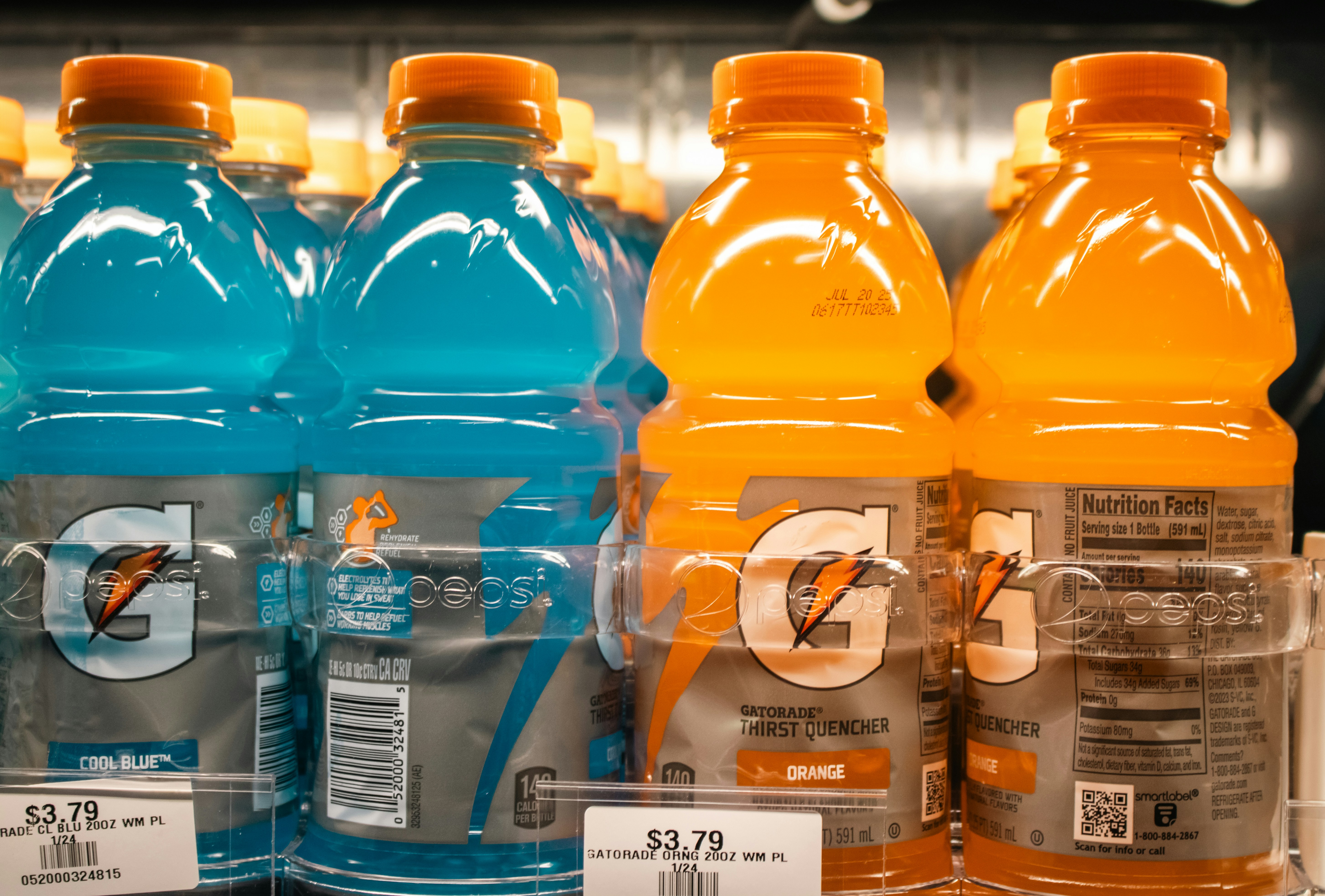 Bottles of blue and orange sports drinks on a store shelf.