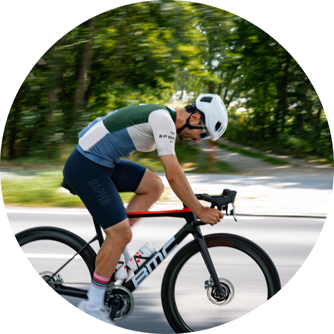 Cyclist in motion on a road bike, wearing a helmet and cycling gear.