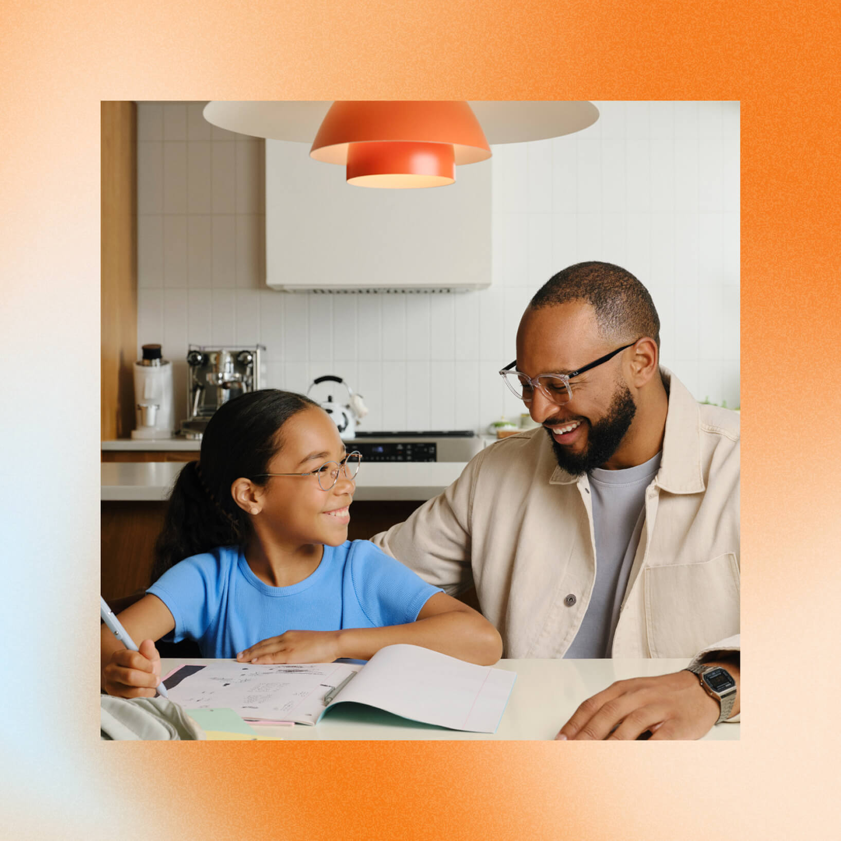 Un homme et une jeune fille souriants faisant des devoirs à la table de la cuisine.