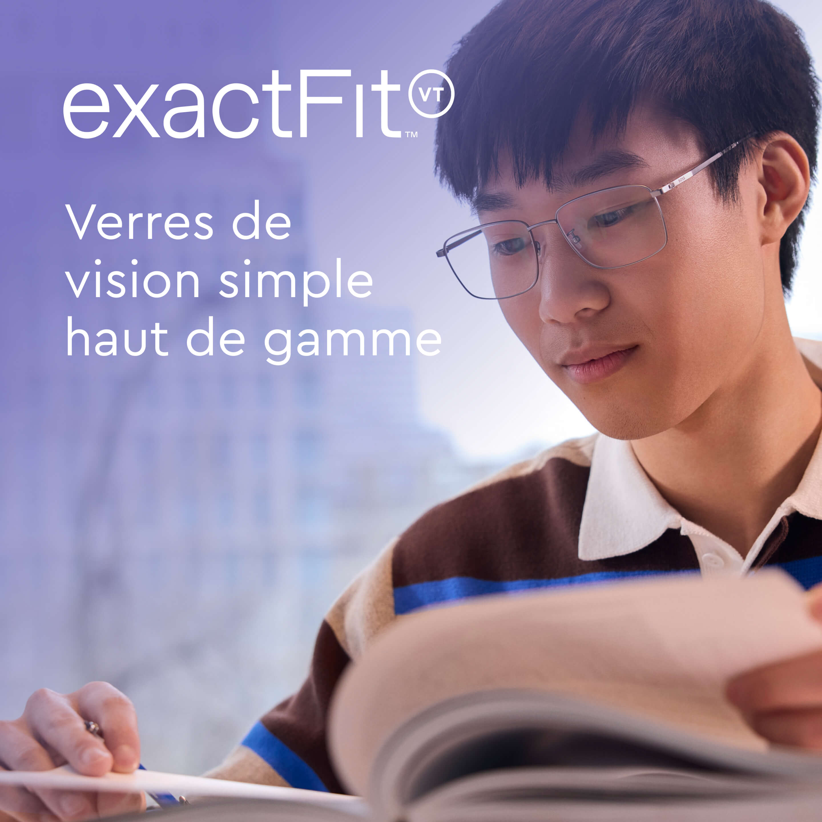 Jeune homme portant des lunettes et un polo rayé qui baisse les yeux en lisant un livre.