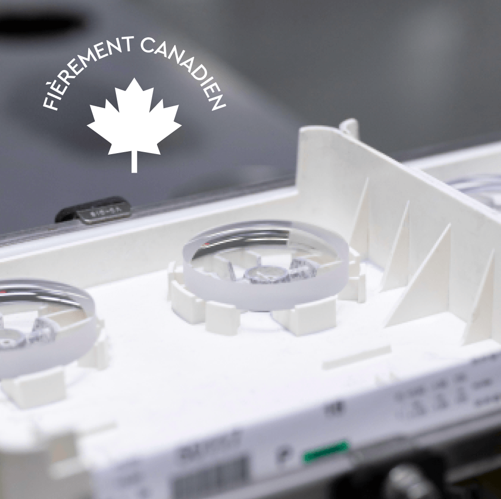 Gros plan de composants optiques dans un plateau de fabrication blanc avec le logo « Fièrement canadien » en surimpression.
