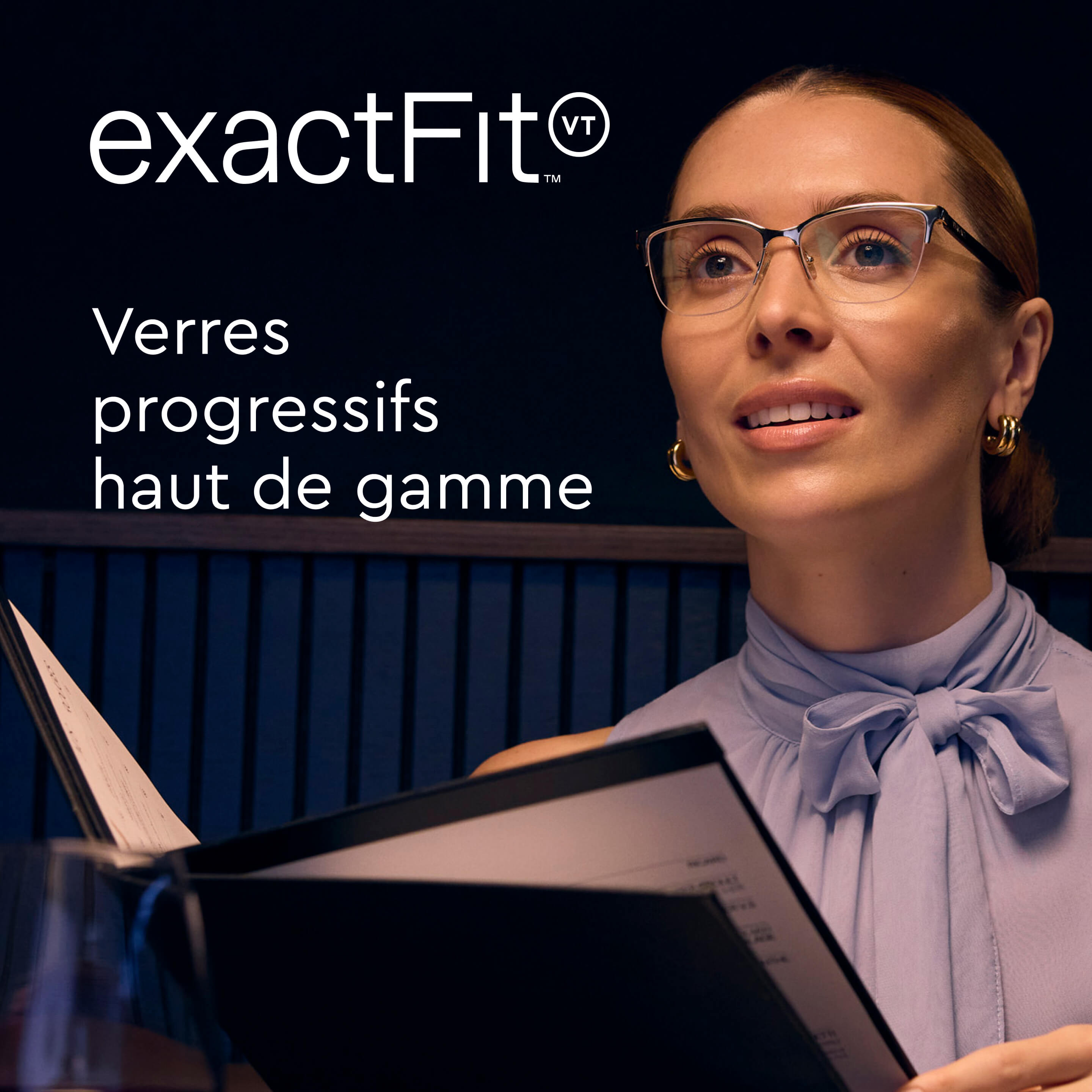 Femme portant des lunettes et un chemisier violet qui lève les yeux d’un menu dans un restaurant faiblement éclairé.
