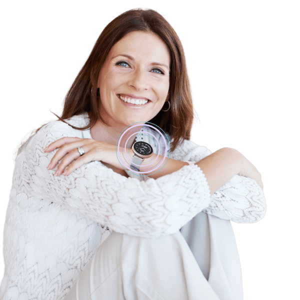 Smiling woman in white sweater sitting with arms crossed over knees.