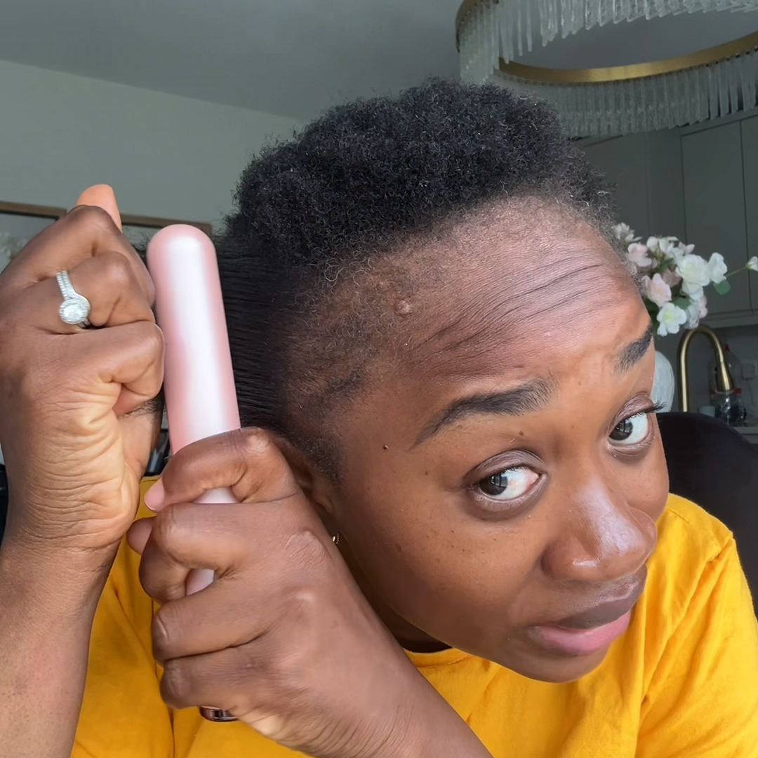 Person styling short hair with a pink brush.