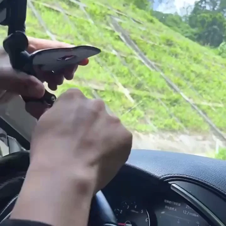 A person's hands adjust a suction cup mount on the inside of a car windshield.