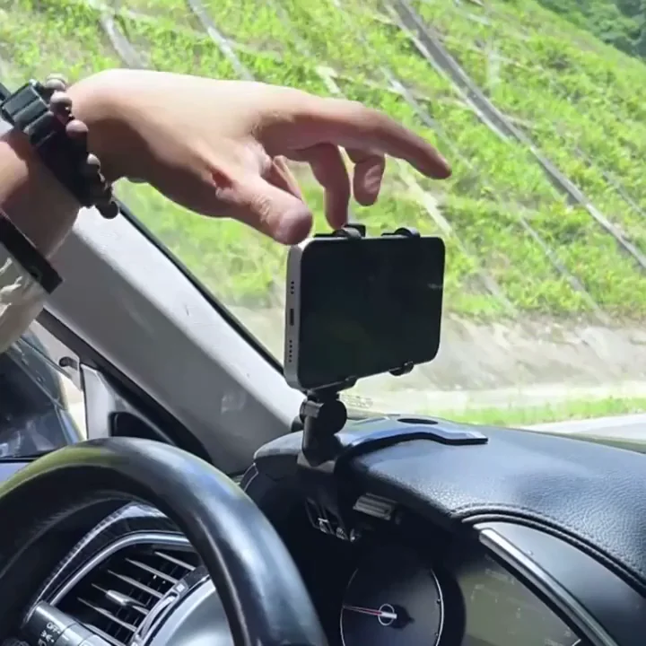 A hand places a smartphone into a holder mounted on a car's dashboard.