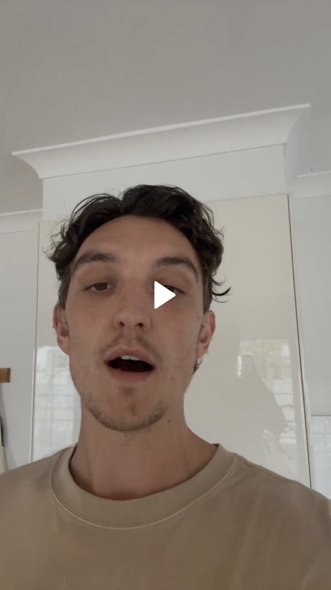 Person speaking in a room with white walls and a cabinet.