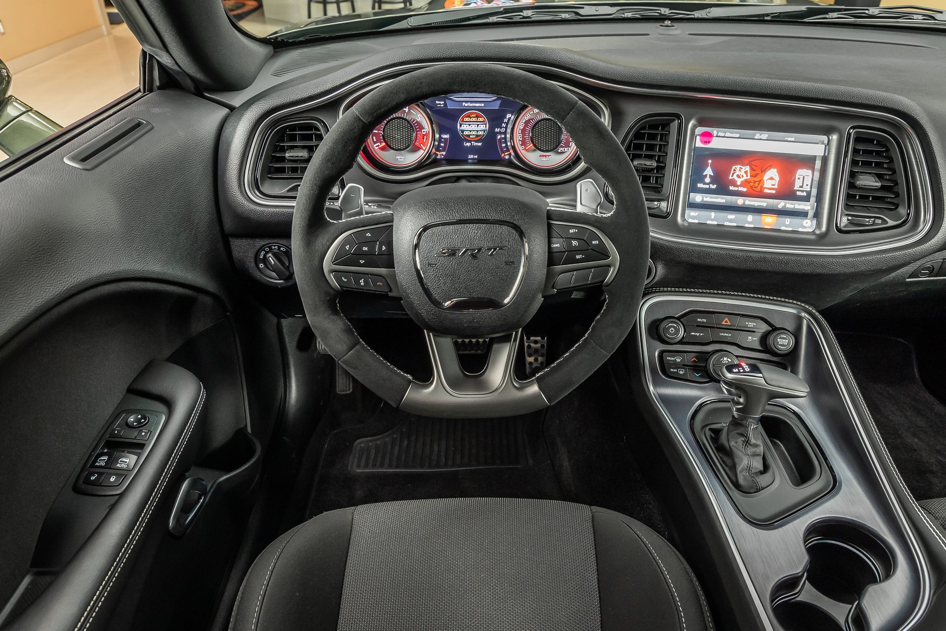 The driver-side interior of a Dodge Challenger SRT, showing the steering wheel, dashboard, and center console.