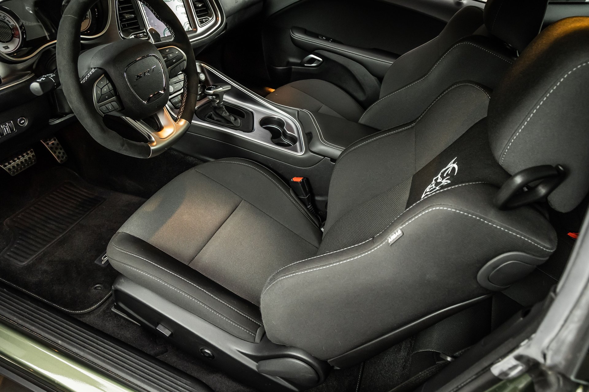 The interior of a car, focusing on the black fabric front seats with an SRT steering wheel.