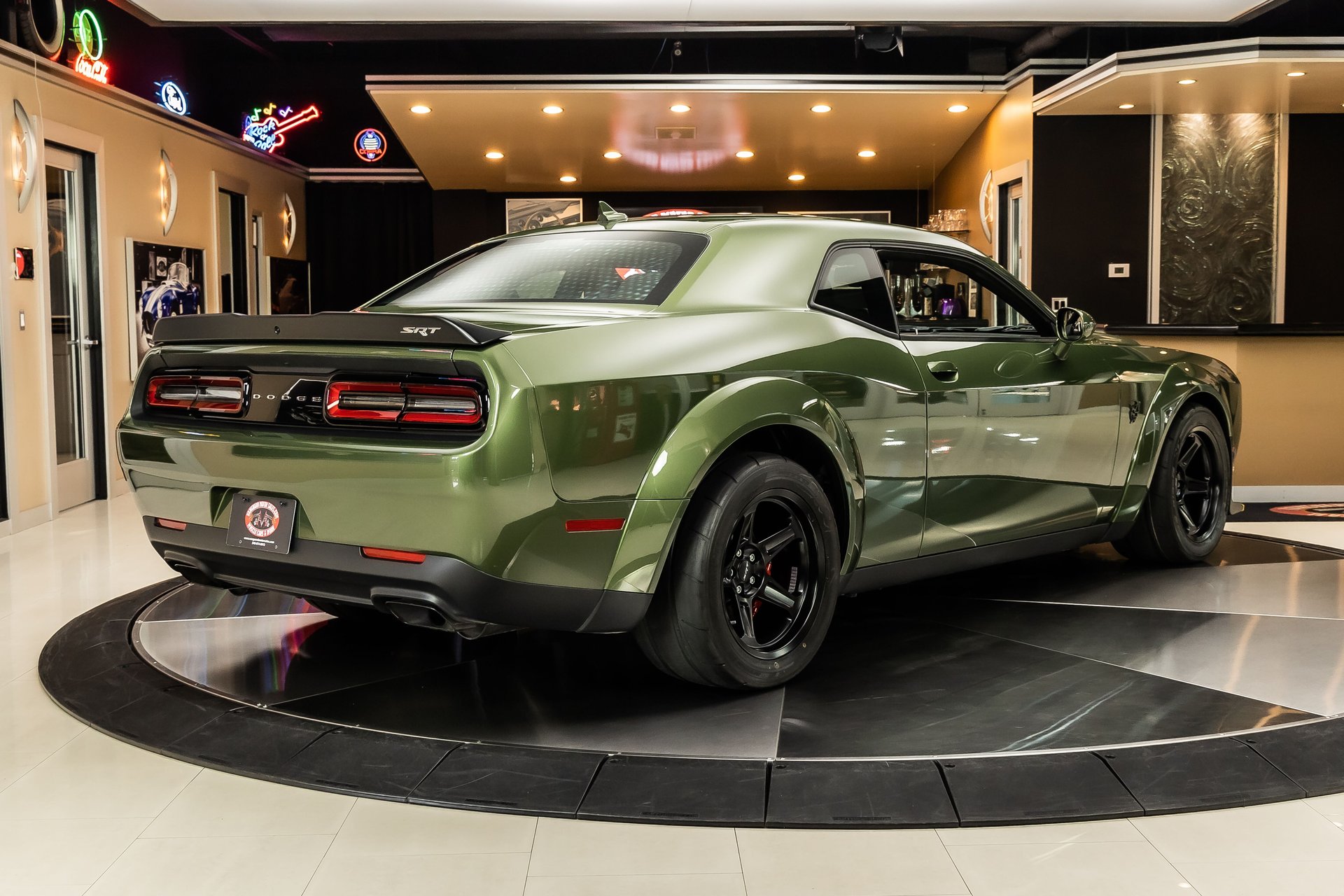 Rear three-quarter view of a green Dodge Challenger SRT on a rotating showroom display platform.