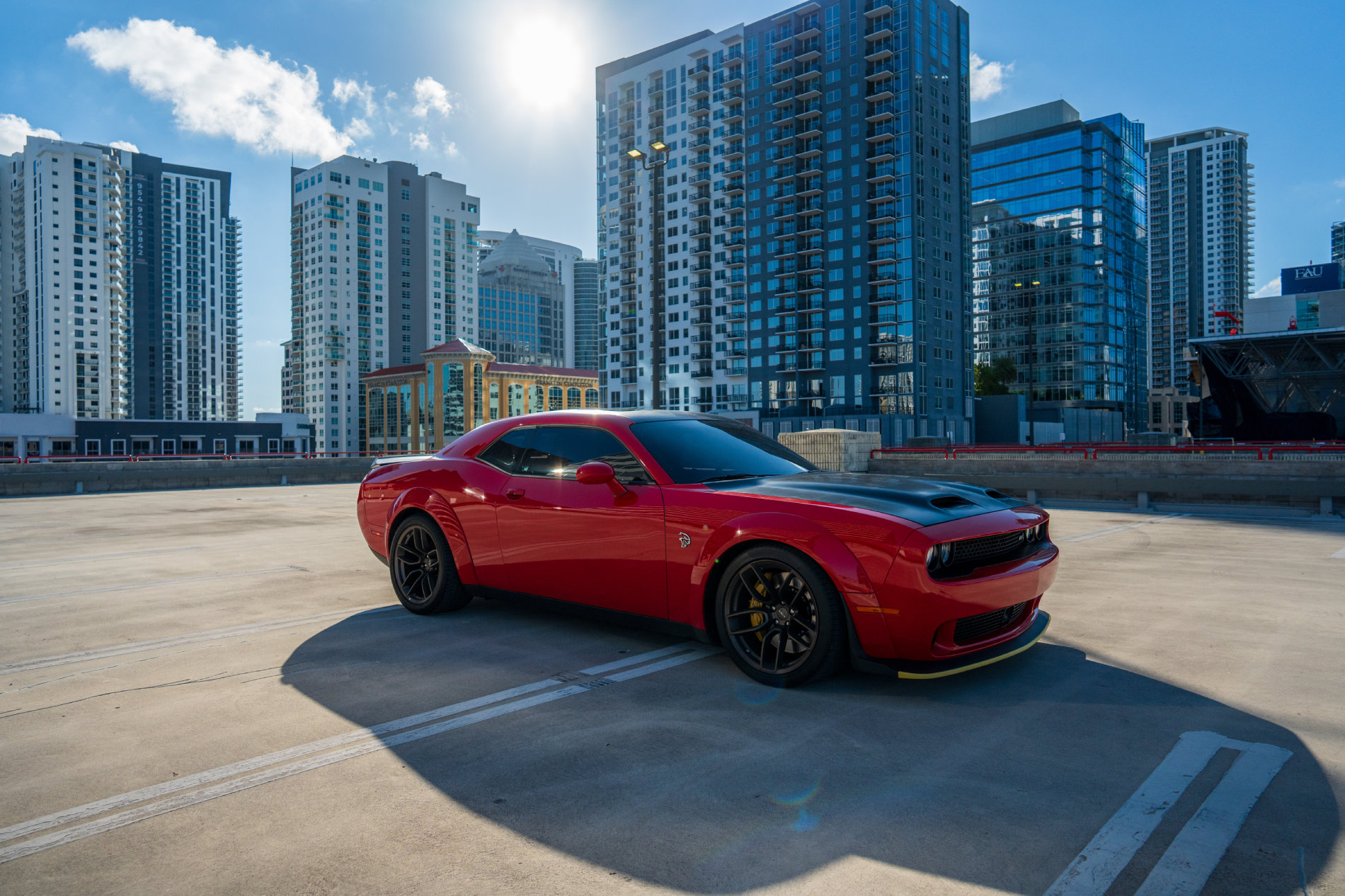 Red car parked on rooftop with city skyscrapers in background.