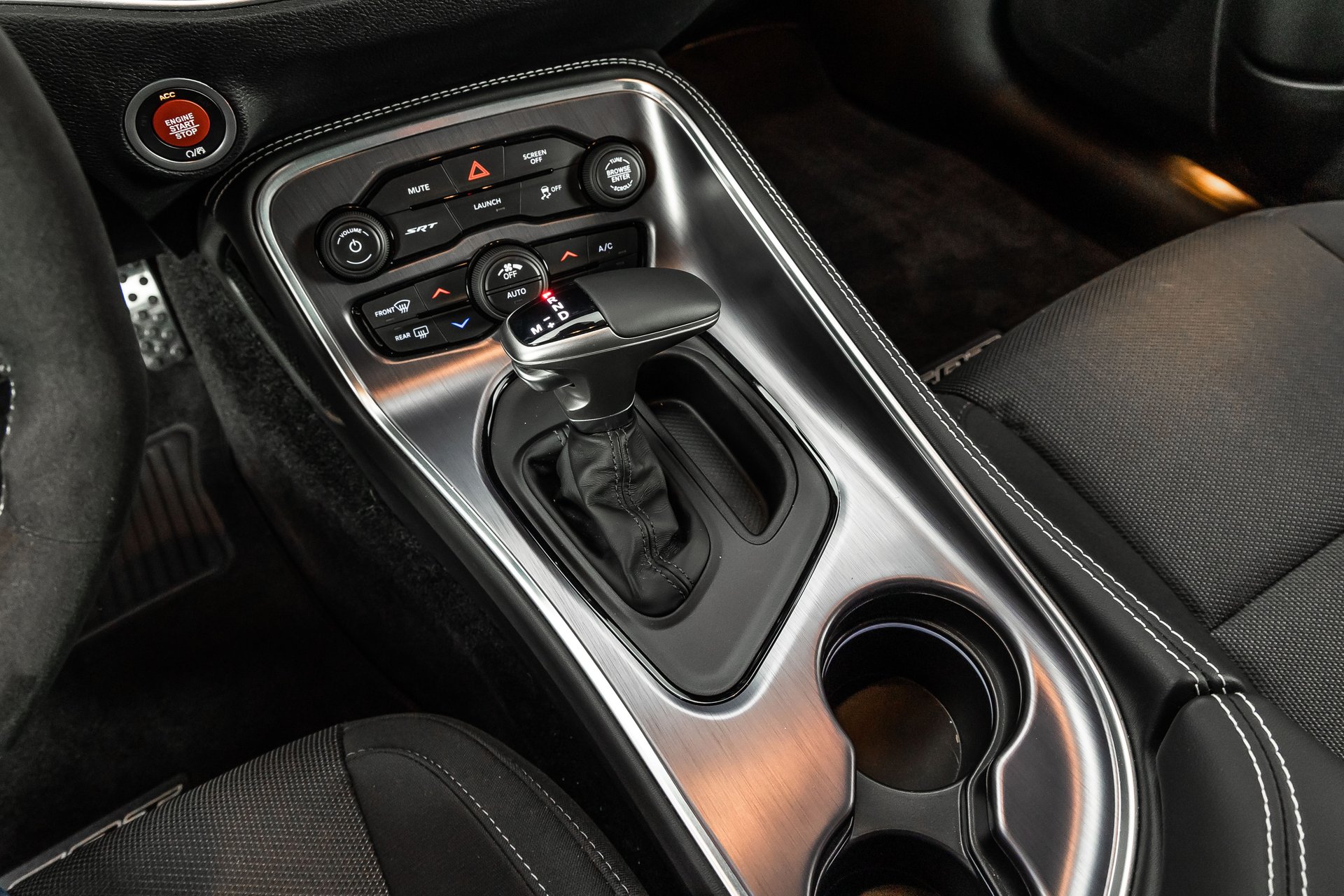 Close-up of a car's automatic gear shifter and center console with brushed metal trim and various control buttons.