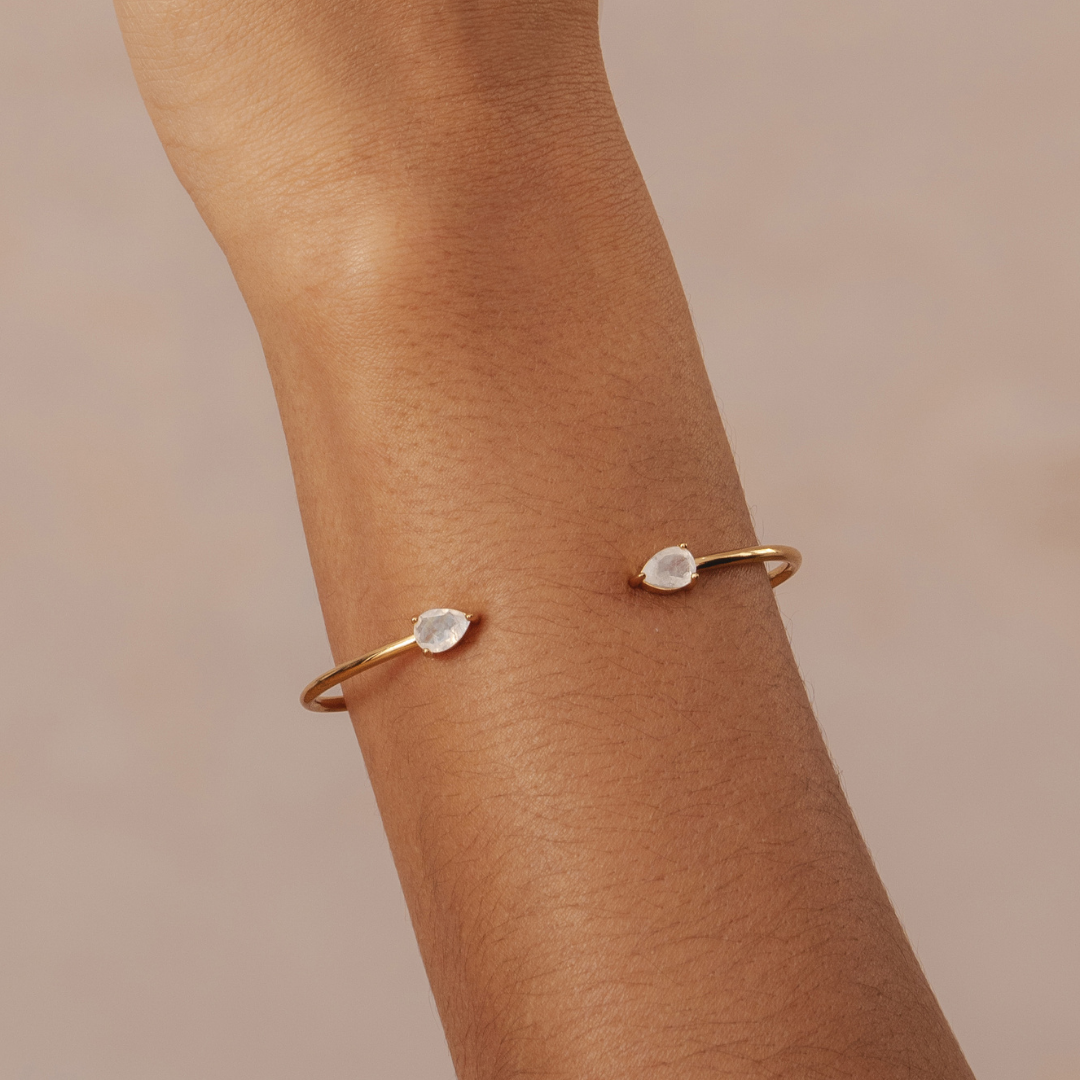Gold bracelet with two gemstones on a person's wrist.