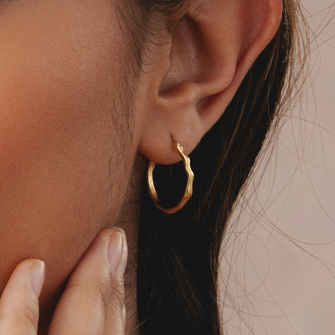 Close-up of an ear wearing a gold hoop earring.