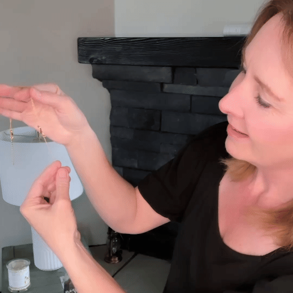 Person holding and examining a pair of dangling earrings.