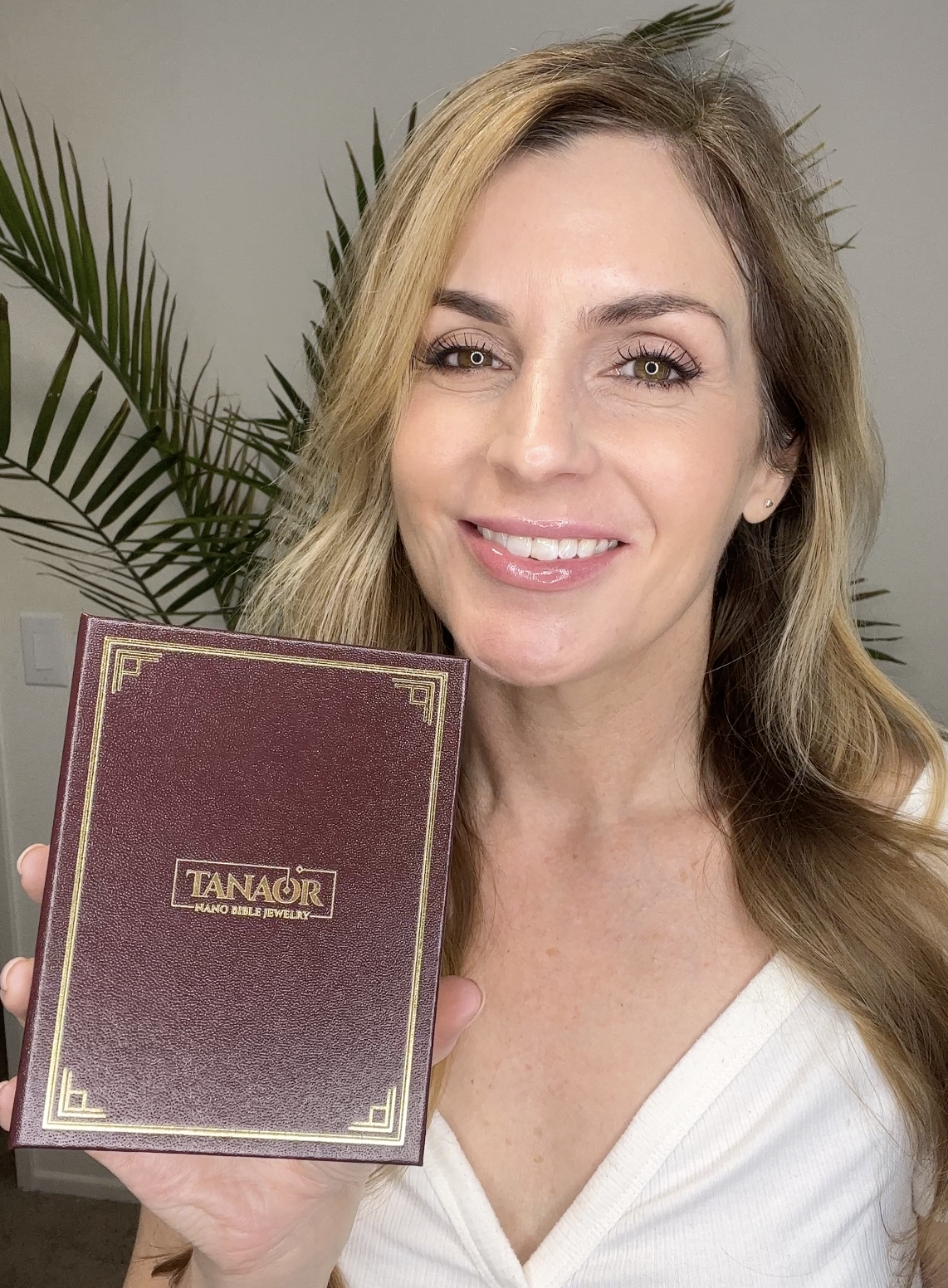 Person holding a maroon book with gold lettering, smiling.