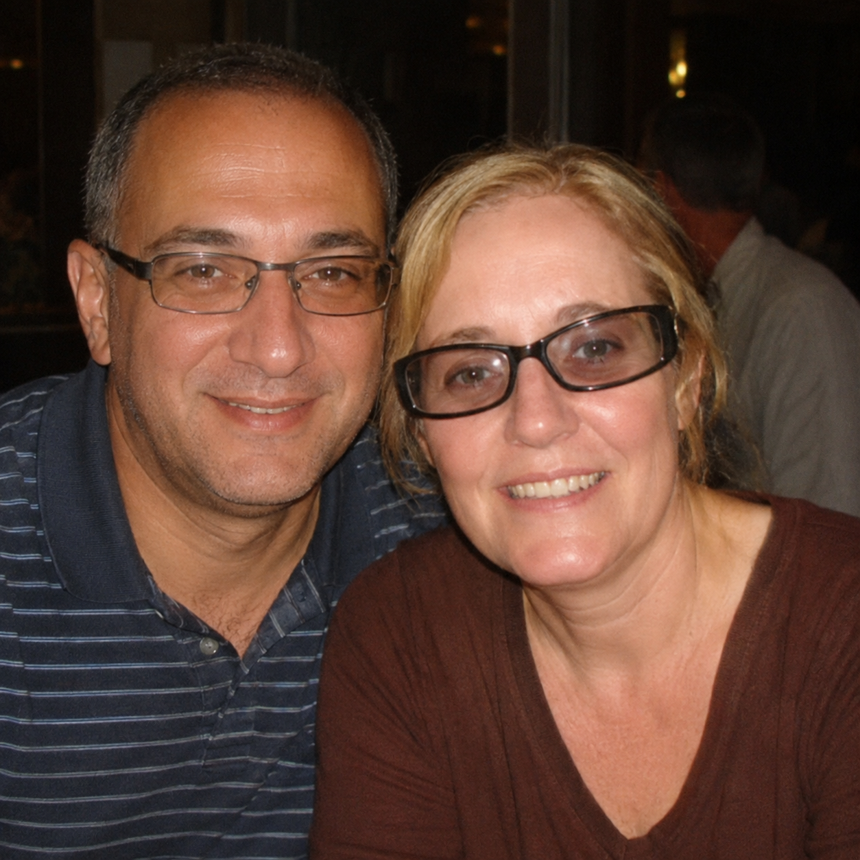 A man and a woman, both wearing glasses, smiling for the camera.